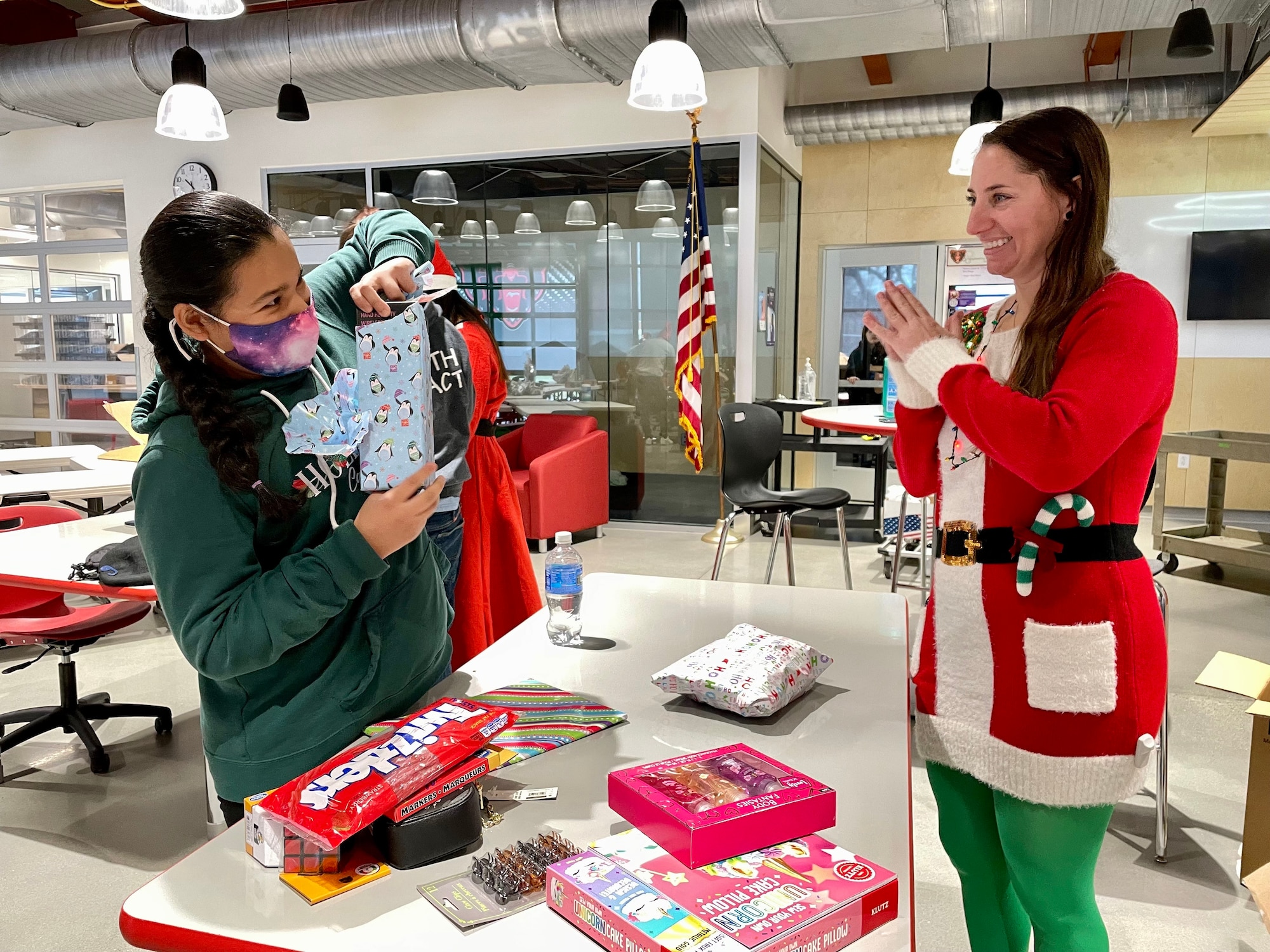 Master Sgt. Sara Kunze, reservist in the 67th Aerial Port Squadron, celebrates alongside Mayte as she opens Christmas gifts provided by the squadron.