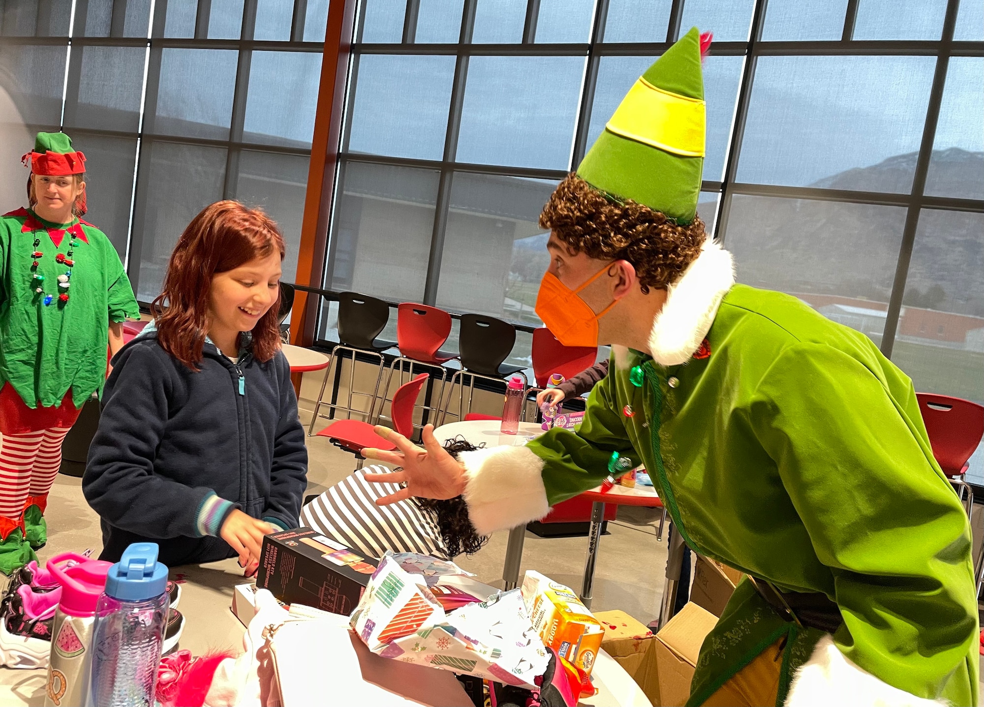 Master Sgt. Daron Nelson, reservist in the 67th Aerial Port Squadron, reacts as Nevaeh unpacks a box full of gifts provided by the squadron.