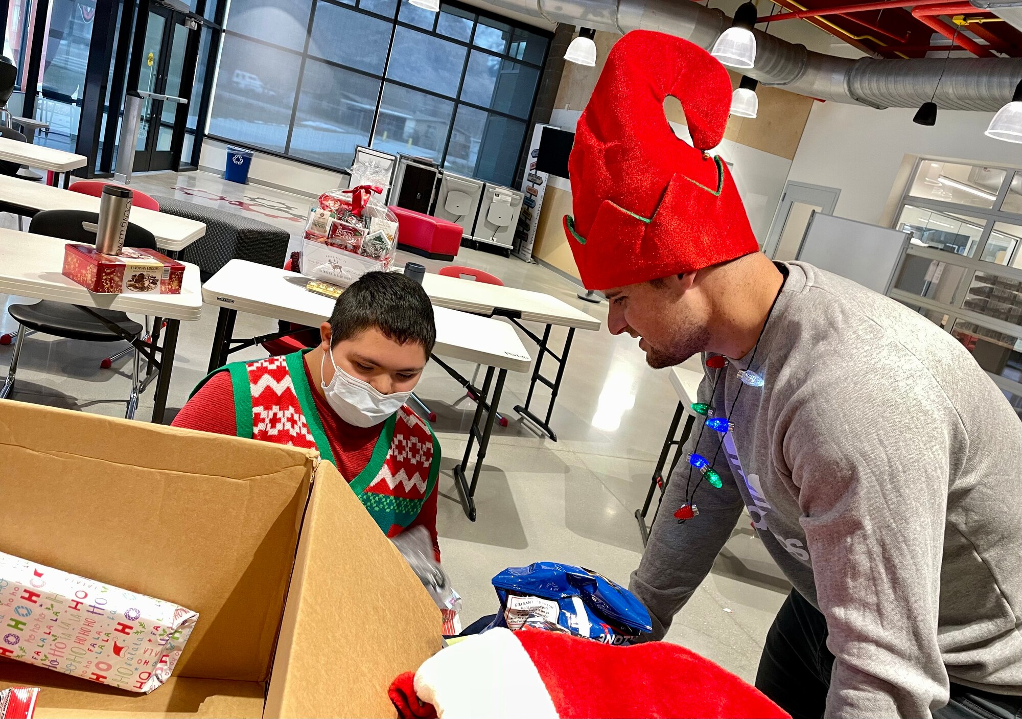 Senior Airman Drew Frandsen, reservist in the 67th Aerial Port Squadron, helps Martin unpack a box full of gifts provided by the squadron.