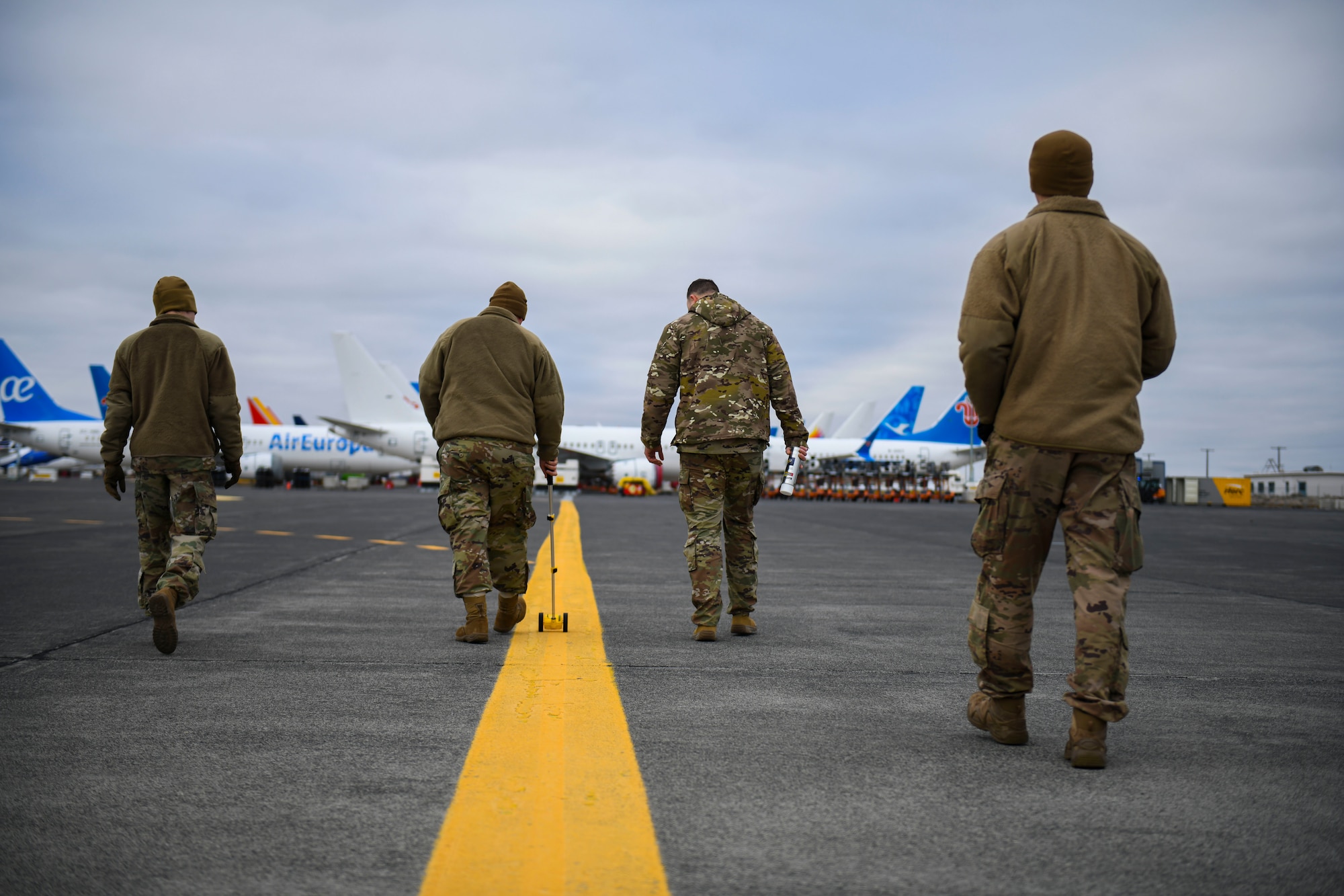 U.S. Air Force Airmen from the 92nd Maintenance Squadron, the 92nd Security Forces Squadron, and the 92nd Operations Support Squadron, measure the distance on a flightline for a potential parking spot for a KC-135 Stratotanker at Grant County International Airport in Moses Lake, Washington, Dec. 6, 2021. The Airmen were prepared to accomplish the primary mission of agile combat employment from a civilian airfield and adapt and prepare for an emergency diversion of four additional aircraft, including a KC-46 Pegasus, an aircraft most Airmen were not familiar with. (U.S. Air Force photo by Senior Airman Kiaundra Miller)