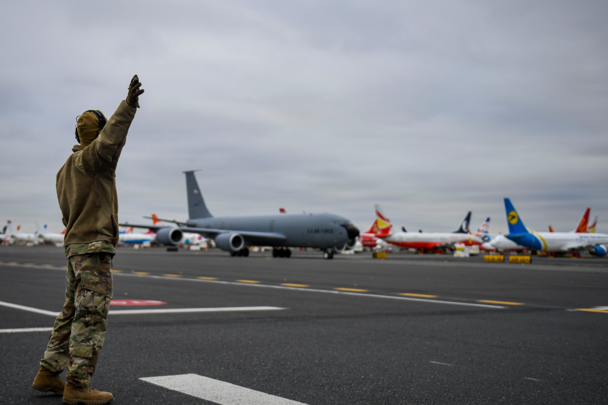 U.S. Air Force Staff Sgt. Cameron Harris, 92nd Operations Support Squadron crew communications technician and noncommissioned officer in charge, marshals a KC-135 Stratotanker at the Grant County International Airport flightline in Moses Lake, Washington, Dec. 7, 2021. Despite being a crew communications technician, Harris was capable of directing a KC-135 Stratotanker due to the skills he learned through multi-capable Airmen training concepts. (U.S. Air Force photo by Senior Airman Kiaundra Miller)