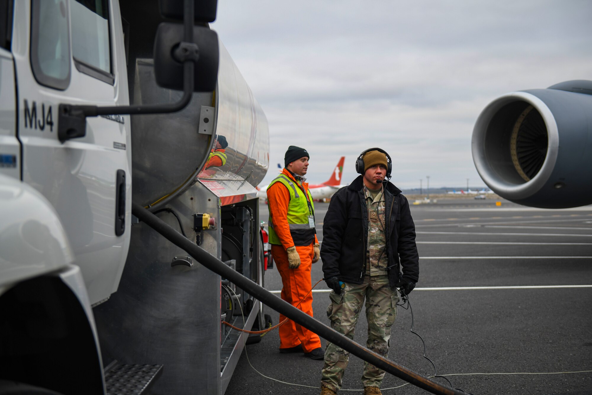 U.S. Air Force Senior Airman Christopher Smith, 92nd Logistics Readiness petroleum, oil, and lubricants technician, speaks with a member from Million Air Aviation Company, while performing hot-pit refueling on a KC-135 Stratotanker at the Grant County International airport in Moses Lake, Washington, Dec. 7, 2021. Building and strengthening joint partnerships with the local community is vital to future successes for the U.S. Air Force to compete and win in a peer-to-peer fight. (U.S. Air Force photo by Senior Airman Kiaundra Miller)