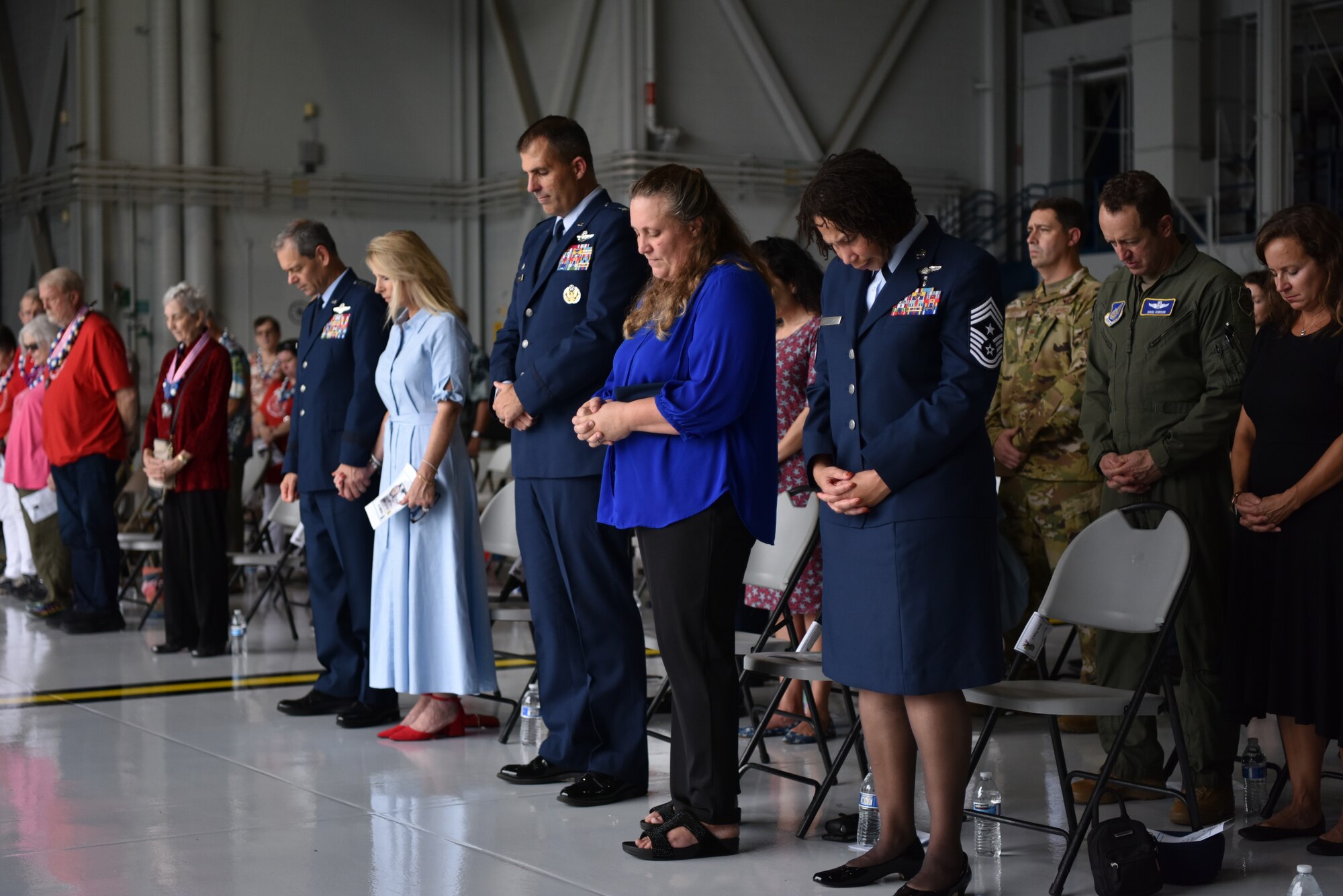 Gen. Ken Wilsbach, PACAF commander, Cindy Wilsbach, First Lady of PACAF, Col. Daniel Dobbels, 15th Wing commander, Lisa Dobbels, spouse, and Chief Master Sgt. Sheronne King, 15 WG command chief, bow their heads during the invocation during the December 7th Remembrance Ceremony at Joint Base Pearl Harbor-Hickam, Hawaii, Dec. 7, 2021. Service members from past and present came together to remember the 80th anniversary of the attacks on Pearl Harbor and Hickam Field that claimed the lives of 189 service members, wounded 303 others, and rendered nearly all aircraft stationed on Hickam useless as the result of the attacks. (U.S. Air Force photo by 1st Lt. Benjamin Aronson)