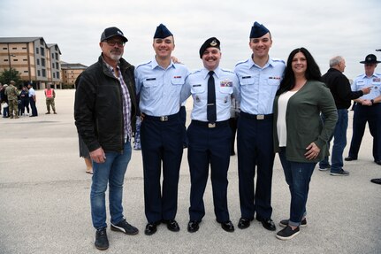 Then Staff Sgt. Zachary Smith (center), an enlisted accessions recruiter with the 313th Recruiting Squadron in New Hartford, New York, poses for a photograph with his identical twin brothers (Cameron and Calvin) and their parents, Dan Smith (left) and Andrea Pelascini, in Airman’s Arena at Joint Base San Antonio-Lackland, Texas, on Nov. 24, 2021.