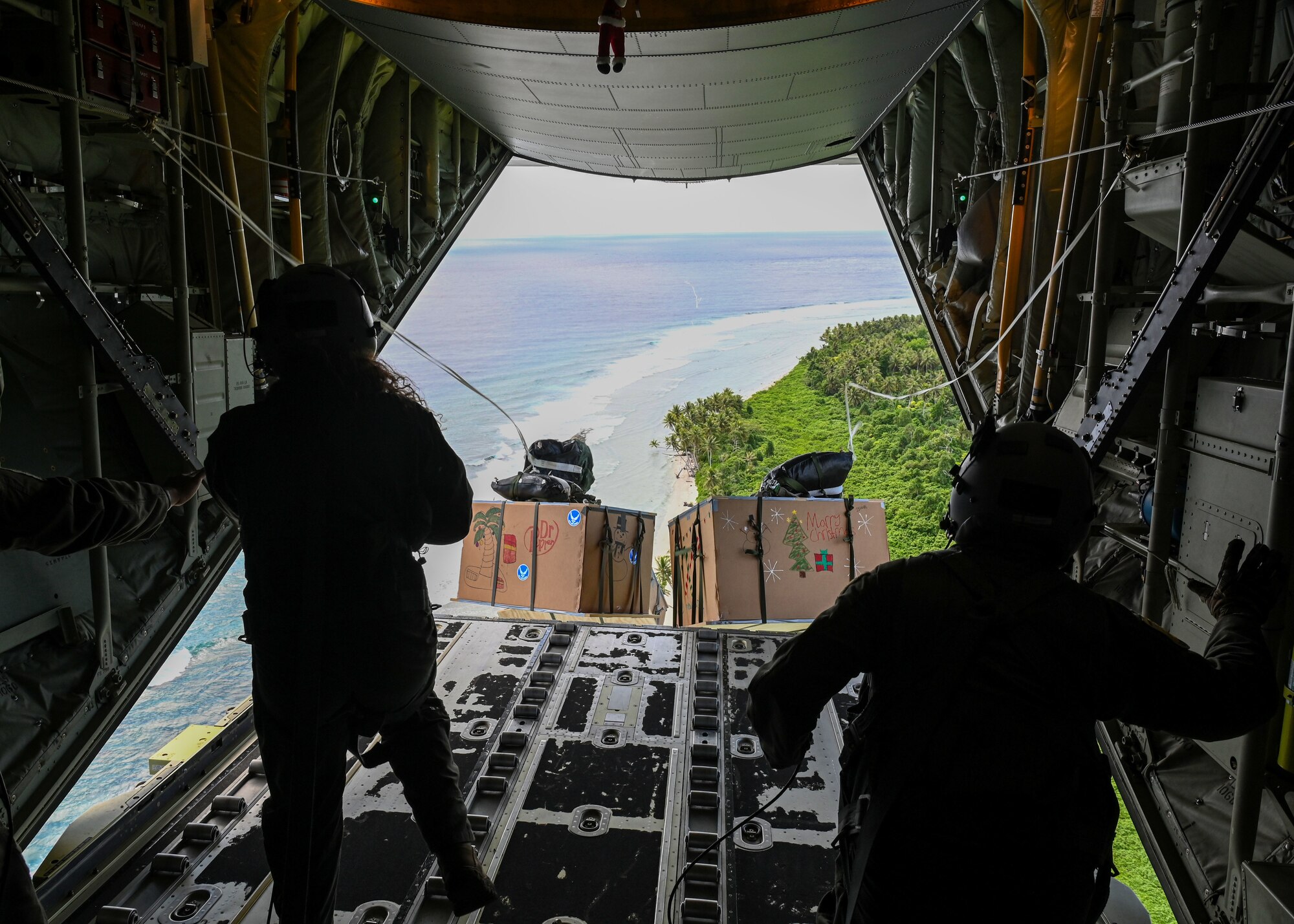 U.S. Air Force Senior Airman Kim Doyle, and U.S. Air Force Airman 1st Class Spencer Kans, loadmasters assigned to the 36th Airlift Squadron, Yokota Air Base, Japan, watch as bundles fly off an aircraft during Operation Christmas Drop at Andersen Air Force Base, Guam, Dec. 10, 2021. Over the course of 10 days, crews will airdrop donated food, clothing, educational materials, and tools to 55 islanders throughout the South-Eastern Pacific, including the Federated States of Micronesia, and the Republic of Palau. (U.S. Air Force photo by Senior Airman Aubree Owens)