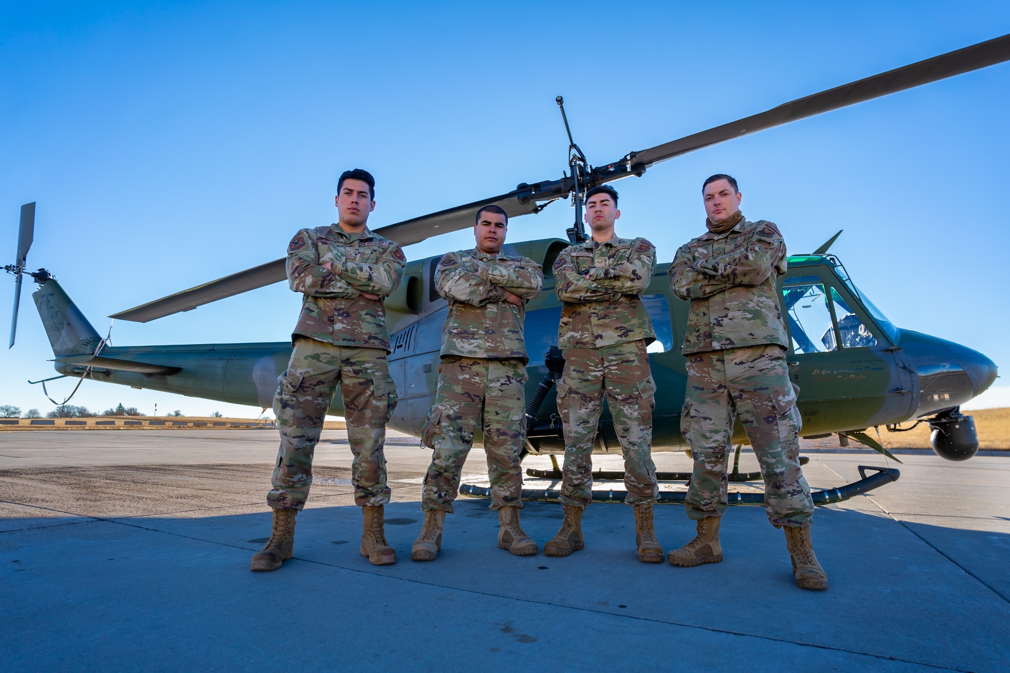 Four Airmen pose for a photo in front of a UH-1N Huey helicopter at F.E. Warren Air Force Base, Wyoming.