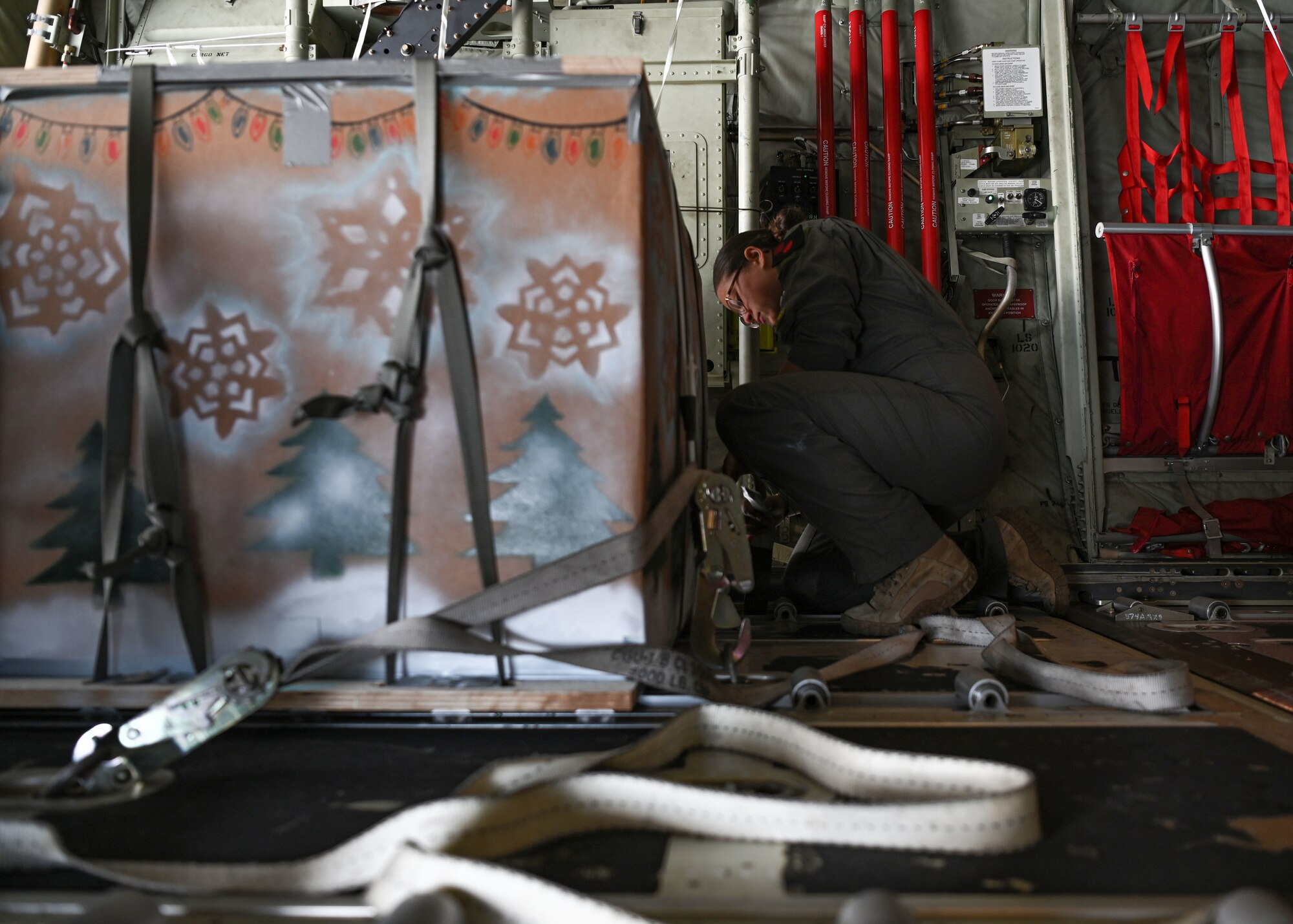 U.S. Air Force Senior Airman Kim Doyle, a loadmaster assigned to the 36th Airlift Squadron, Yokota Air Base, Japan, secures an airdrop bundle on a U.S. Air Force C-130J during Operation Christmas Drop at Andersen Air Force Base, Guam, Dec. 10, 2021. Over the course of 10 days, crews will airdrop donated food, clothing, educational materials, and tools to 55 islanders throughout the South-Eastern Pacific, including the Federated States of Micronesia, and the Republic of Palau. (U.S. Air Force photo by Senior Airman Aubree Owens)