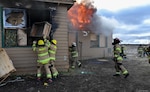 Kingsley Field Firefighters load fuel into a burning structure during a “Burn-to-Learn” event in partnership with Klamath Falls, Ore., Fire District One Dec. 8, 2021. The firefighters used a condemned house to study fire behavior, practice coordination with local partners and meet the Air Force requirement for live-fire training.