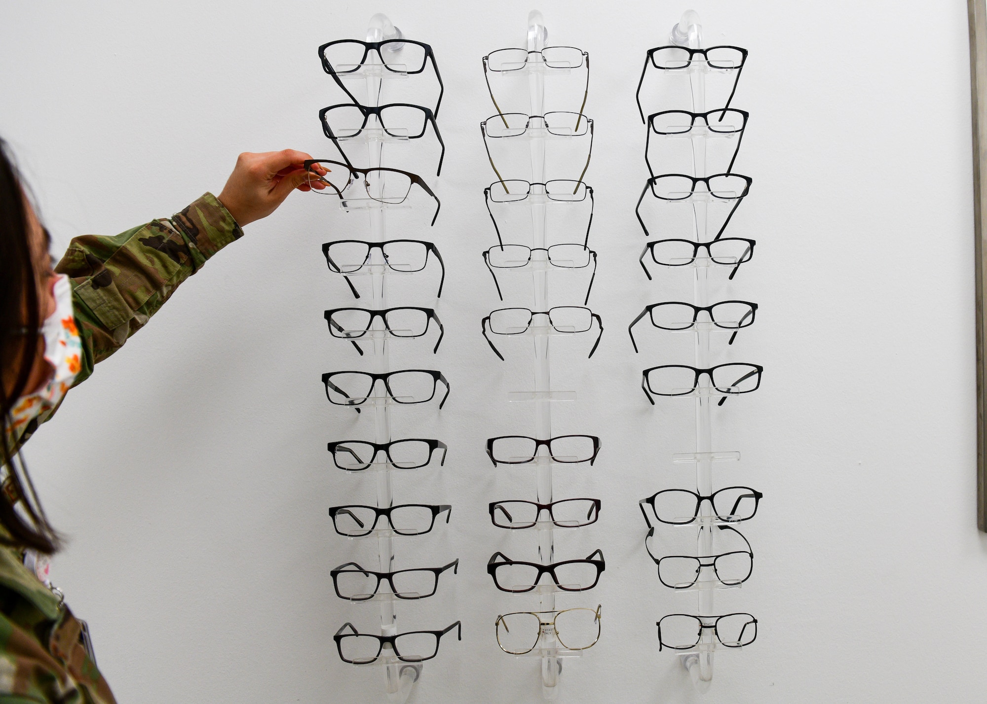Senior Airman Yadira Benzing, 31st Operational Medical Readiness Squadron ophthalmic journeyman, reaches for a pair of glasses at Aviano Air Base, Italy, Dec. 6, 2021. Active duty members are authorized two sets of glasses and a pair of gas mask inserts every 12 months. One pair is a standard issue frame, like the ones at basic training and the second pair is the ‘frame of choice.’ (U.S. Air Force photo by Senior Airman Brooke Moeder)