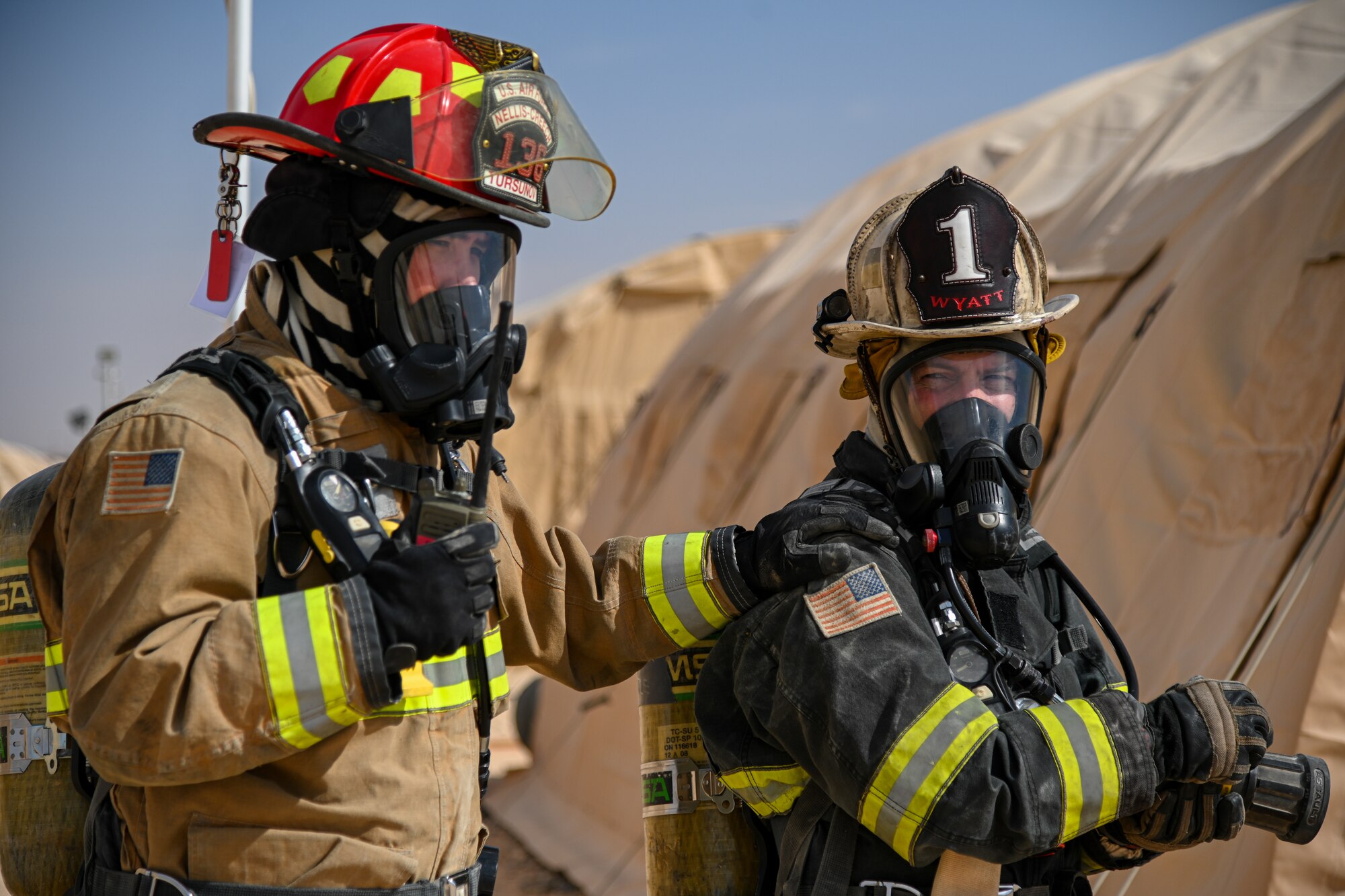 U.S. Air Force Staff Sgt. Sanjar Tursunov, left, 378th Expeditionary Civil Engineer Squadron firefighter, and Brig. Gen. Robert Davis, right, 378th Air Expeditionary Wing commander, prepare to extinguish a simulated structure fire at Prince Sultan Air Base, Kingdom of Saudi Arabia, Dec. 9, 2021. Members of the 378th ECES taught Davis how to don a complete fire suit as well as how to properly extinguish a structure fire. (U.S. Air Force photo by Staff Sgt. Christina Graves)