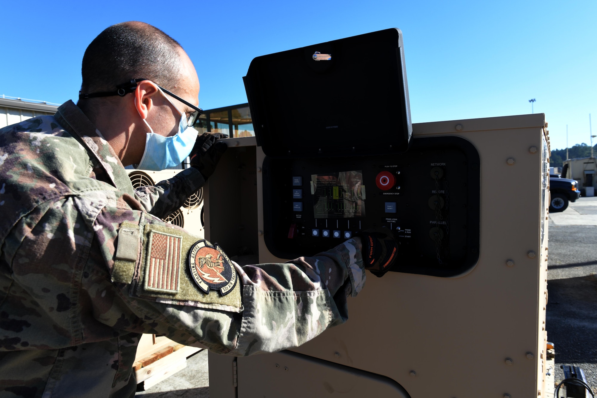 Photo shows Airman outside looking into a large piece of equipment.