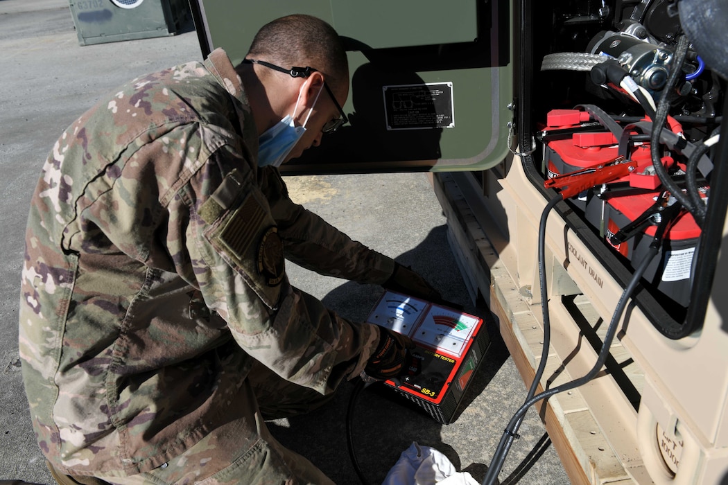 Photo shows Airman outside looking at a meter on equipment.