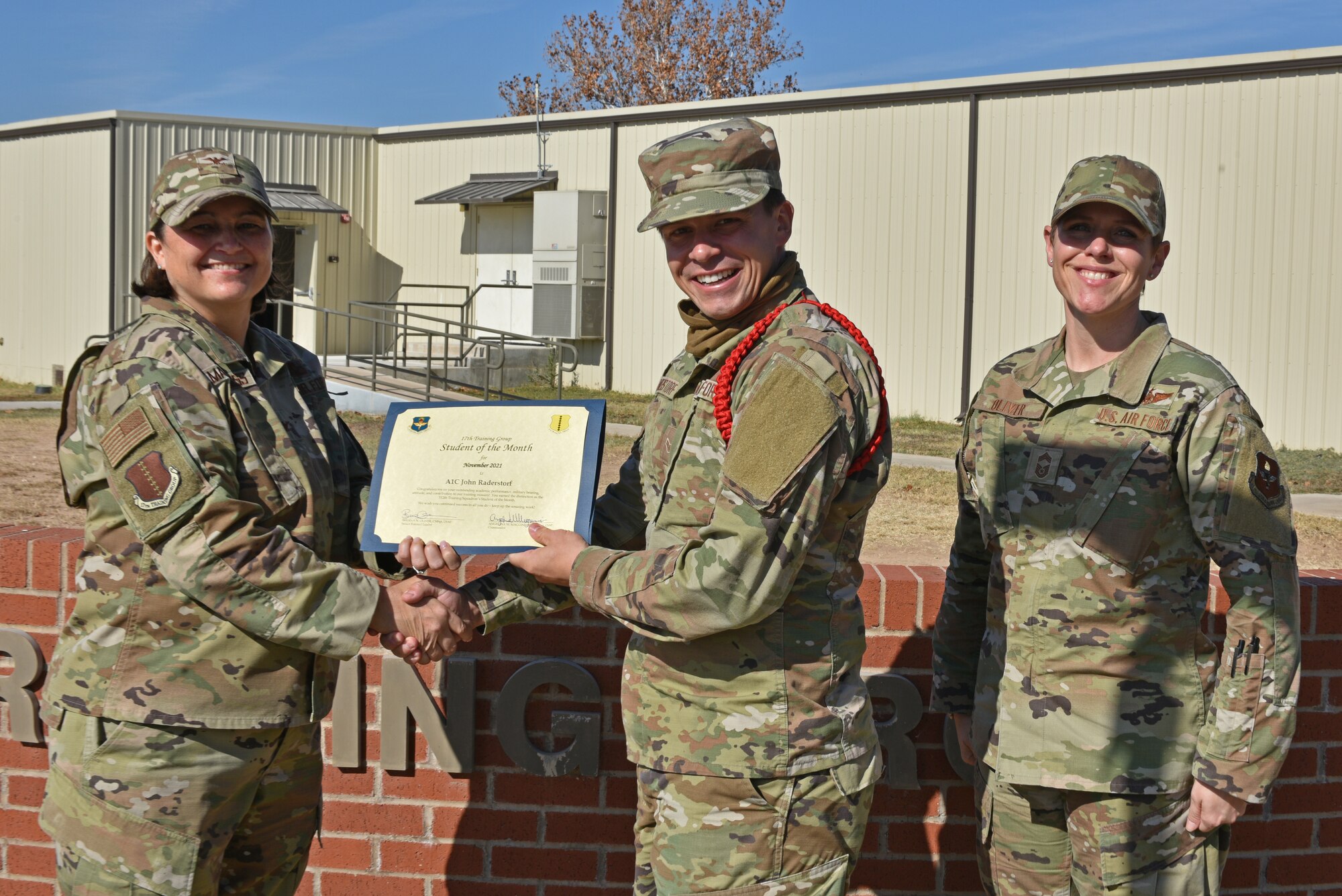 U.S. Air Force Col. Angelina Maguinness, 17th Training Group commander, and Chief Master Sgt. Breana Oliver, 17th TRG superintendent, present Airman 1st Class John Raderstorf, 312th Training Squadron student, the 17th TRS Student of the Month award for November 2021, on Goodfellow Air Force Base, Texas, Dec. 14, 2021. The award highlights his outstanding academic performace.  (U.S. Air Force photo by Senior Airman Ashley Thrash)