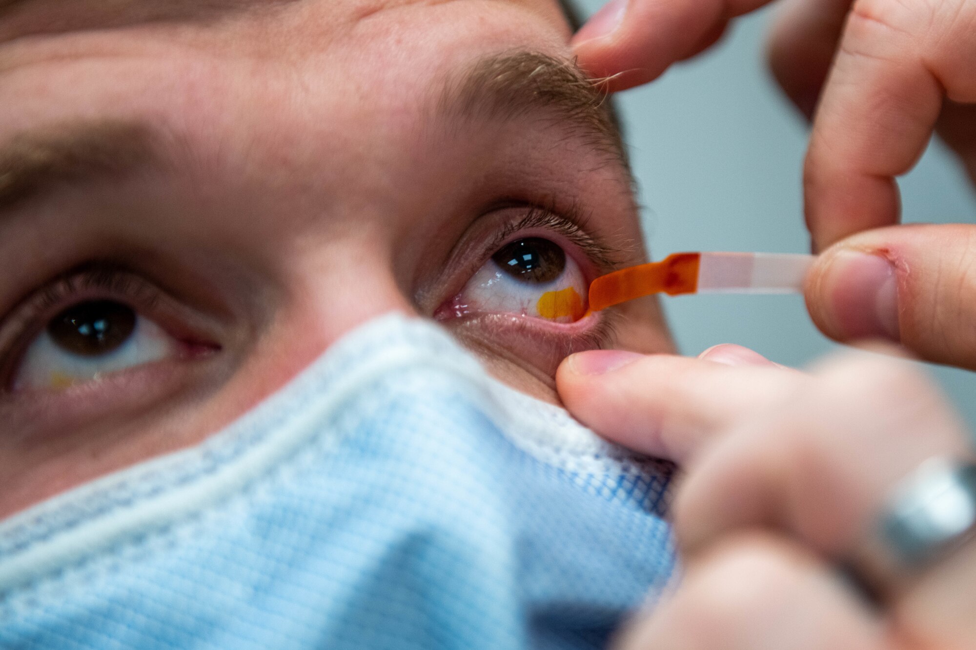 U.S. Air Force Staff Sgt. Dalton Aric, 31st Civil Engineer Squadron firefighter, has a fluorescein strip touch his eye during an eye exam at Aviano Air Base, Italy, Dec. 2, 2021. Fluorescein is used to assist in the detection of debris and corneal abrasions. (U.S. Air Force photo by Senior Airman Brooke Moeder)