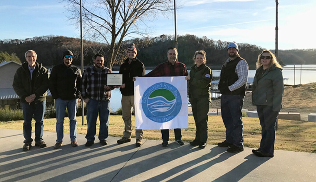 Environmental Protection Specialist Phillip Harrell, Realty Specialist Duane Bryson, Willow Grove Marina Manager Michael Maxwell, Willow Grove Marina employee Blake Ledbetter, Willow Grove Marina owner Mickey Ledbetter, Dale Hollow Lake Park Ranger Sondra Carmen, Biologist Daniel Clark, and Realty Specialist Lori Neubert pose proudly with the Clean Marina flag Nov. 29, 2021 to celebrate Willow Grove Marina’s recertification in the Clean Marina Program at Dale Hollow Lake in Celina, Tennessee.