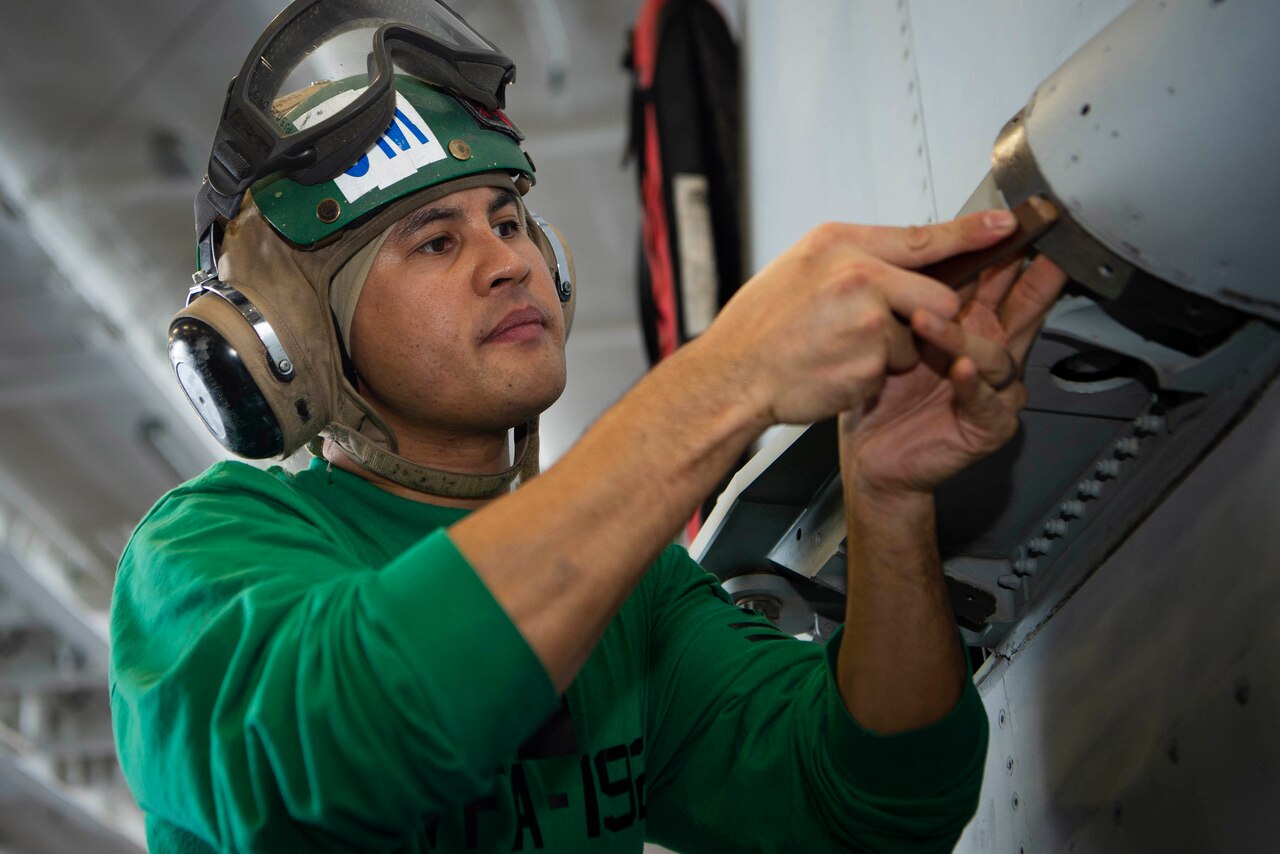 A sailor performs maintenance.