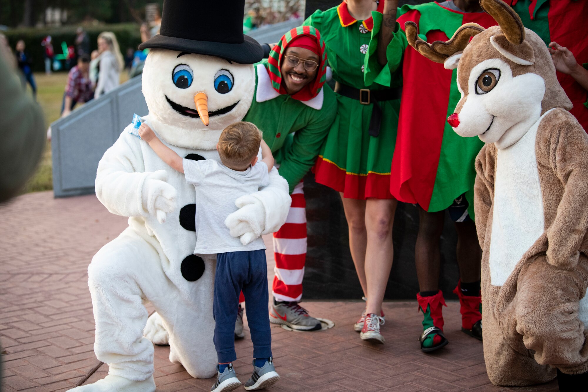 A Team Hurlburt member gives a snowman a hug during the annual tree lighting ceremony