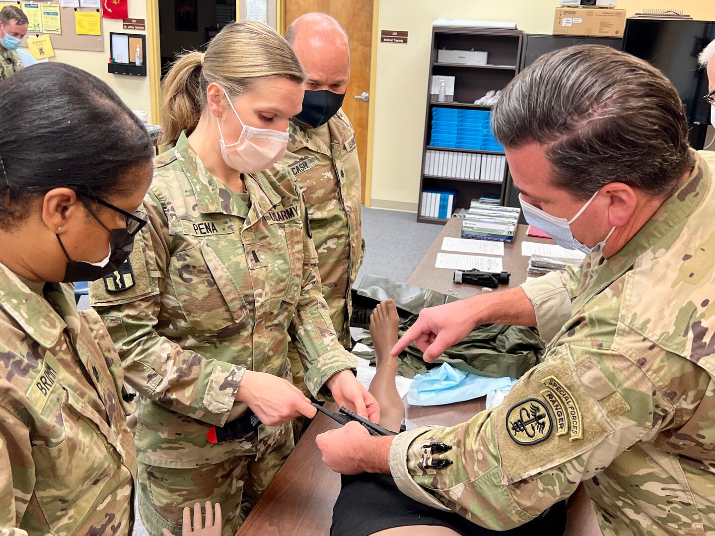 Lt. Col. Jeffery White, orthopedic surgeons, Bayne-Jones Army Community Hospital discusses techniques for applying a tourniquet with 1st Lt Jennifer Pena, battalion physician assistant, 317th Engineer Battalion, 3rd Brigade Combat Team, 10th Mountain Division as Lt. Col. Marcia Brimm and Lt. Col. Daniel Cash, look on during the area of concentration, individual critical task list skills fair Dec. 13 at the Joint Readiness Training Center and Fort Polk, Louisiana.