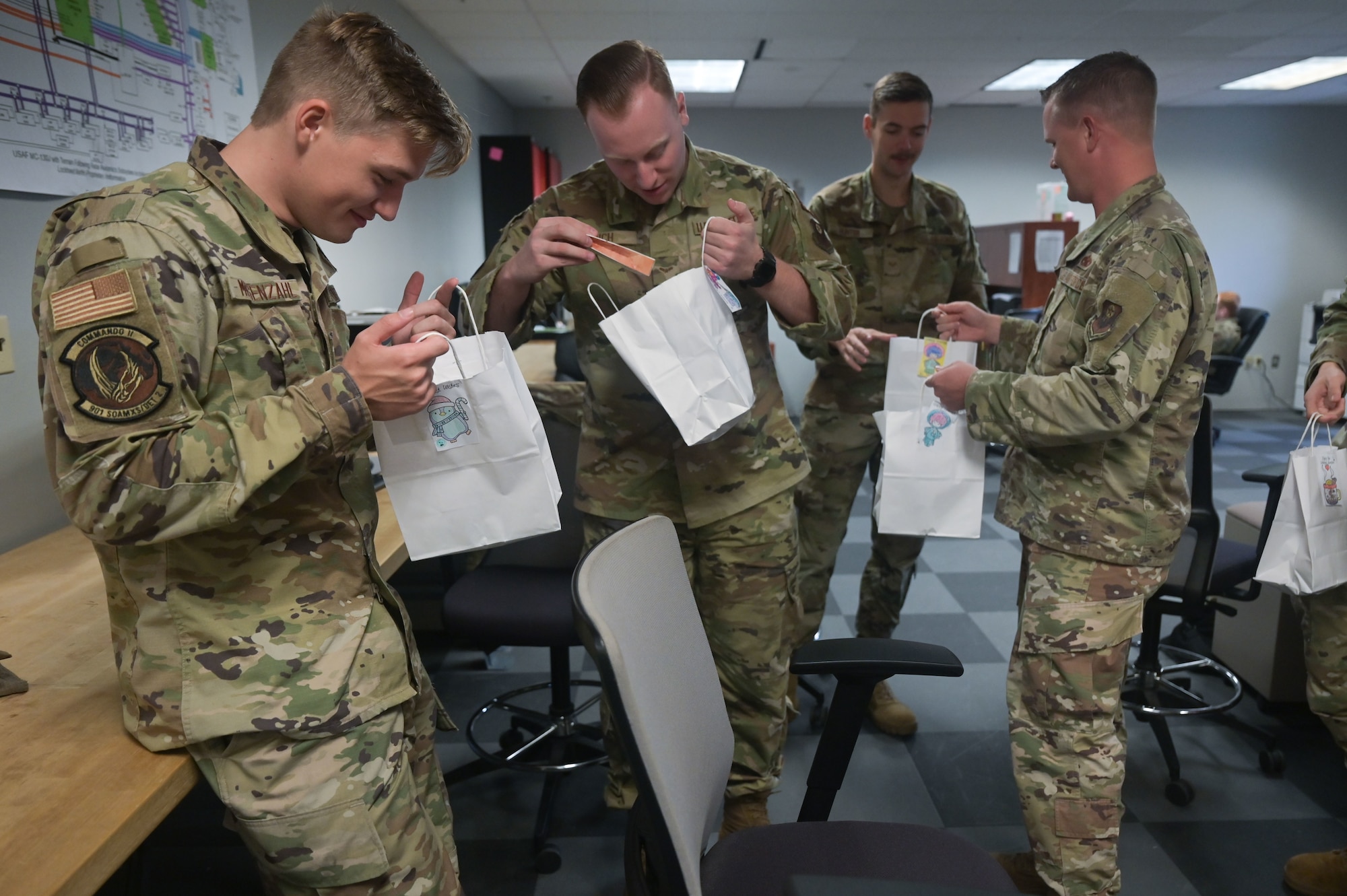 Members with the 901st Special Operations Aircraft Maintenance Squadron open bags containing baked goods from the Commando Cookie Drive