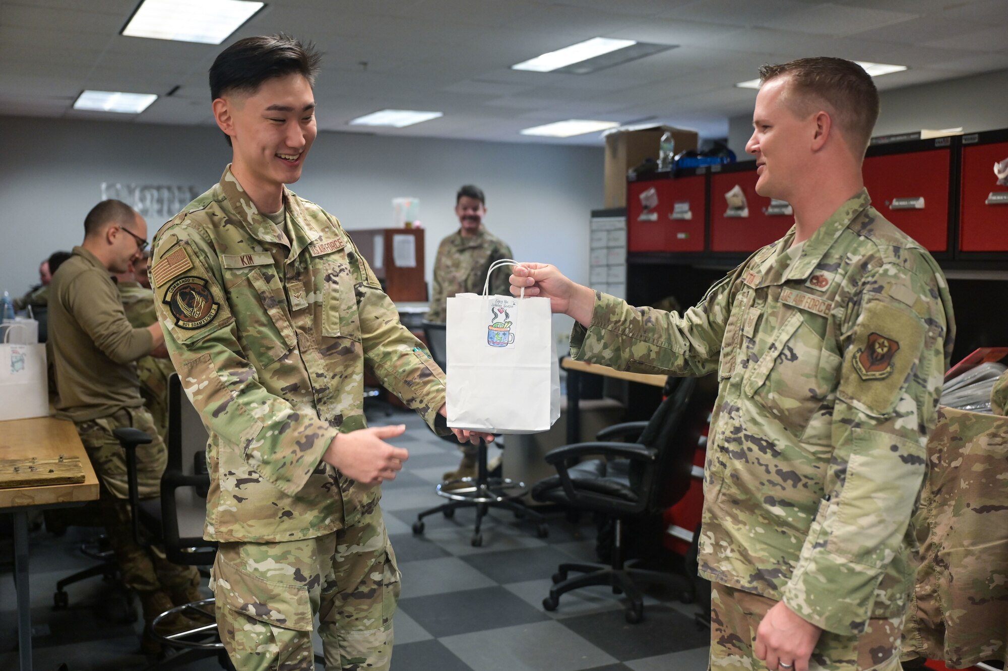 U.S. Air Force Tech Sgt. Kenneth Sutton, the 901st Special Operations Aircraft Maintenance Squadron assistant first sergeant, hands a cookie bag to Airman Sean Kim, a 901st SOAMXS electronic warfare technician