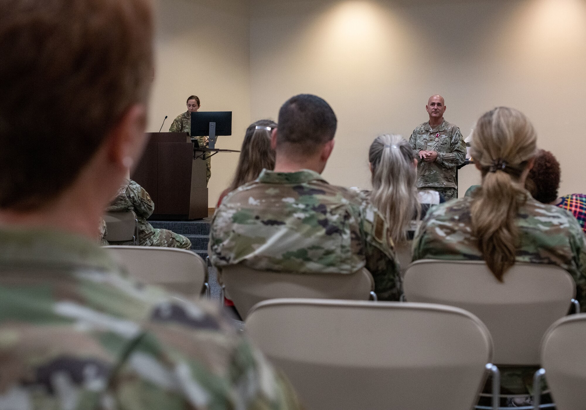 People sit in chairs in the foreground as Col. Fortson speaks in front of them