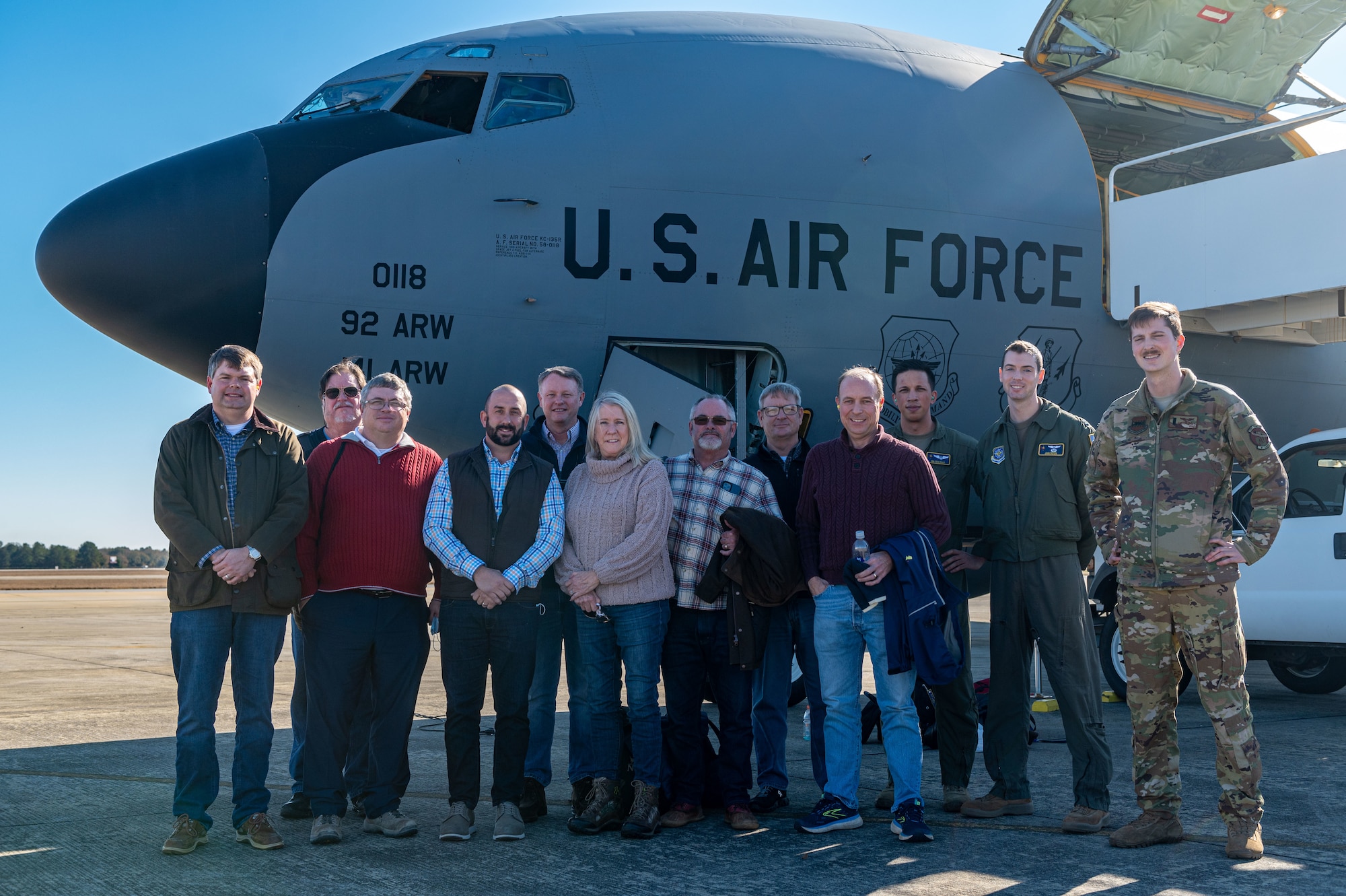 A photo of a group outside of a plane.