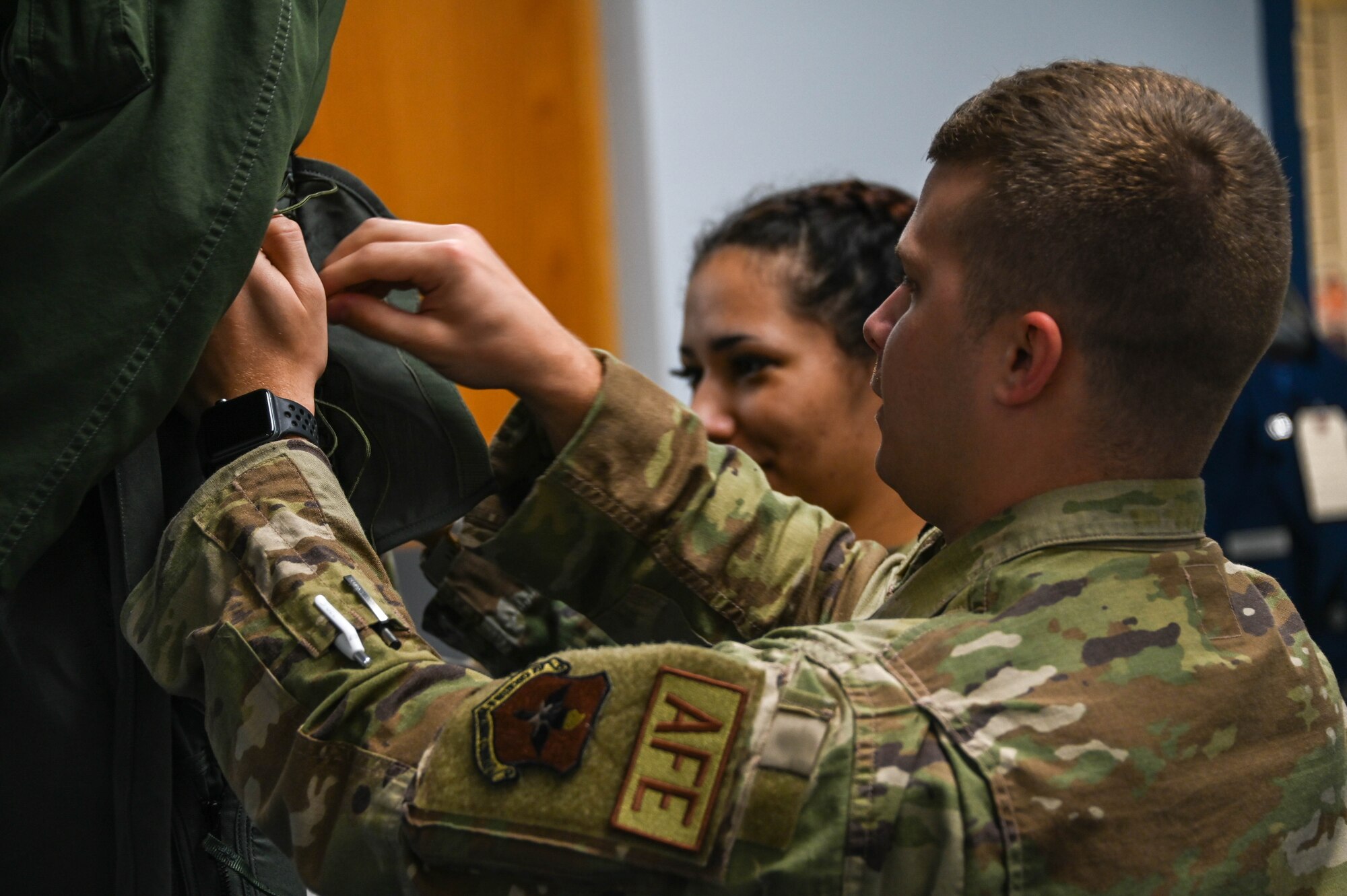 U.S. Air Force Senior Airman Austin Gutt, 47th Operations Support Squadron (OSS) aircrew flight equipment journeyman, and Staff Sgt. Chloe Bettes, 47th OSS aircrew flight equipment technician, tighten the laces on a “G-suit” for Col. Blaine Baker, commander of the 97th Air Mobility Wing at Altus Air Force Base (AFB), Oklahoma, for his T-6 Texan II flight at Laughlin (AFB), Texas, Dec. 9, 2021. The “G-suit” is designed to prevent the pilot from blacking out under extreme acceleration force. (U.S. Air Force photo by Airman 1st Class Kayla Christenson)