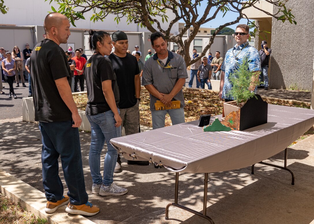 The Kapoi family takes a close-up look at the memorial bonsai tree by Jason Hence. From left to right, Ason Abe - Code 139, Fallyn Kapoi - Code 139, Vernon Kapoi – Shop 38, Vince Kapoi, Sr. – Code 970, Jason Hence, NAVSEA Nondestructive Testing and Welding Programs Manager. (U.S. Navy photo by Dave Amodo released)