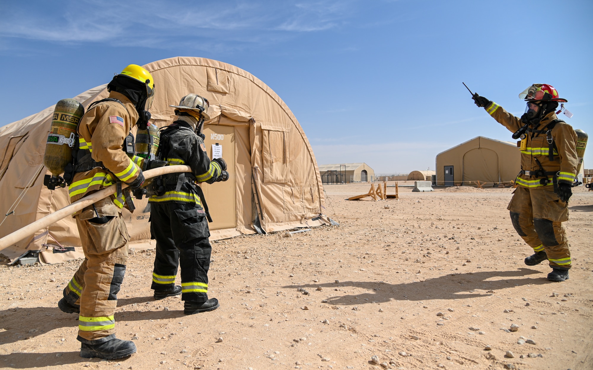 U.S. Air Force Brig. Gen. Robert Davis, center, 378th Air Expeditionary Wing commander, prepares to extinguish a simulated structure fire alongside members of the 378th Expeditionary Civil Engineer Squadron at Prince Sultan Air Base, Kingdom of Saudi Arabia, Dec. 9, 2021. Members of the 378th ECES taught Davis how to don a complete fire suit as well as how to properly extinguish a structure fire. (U.S. Air Force photo by Staff Sgt. Christina Graves)
