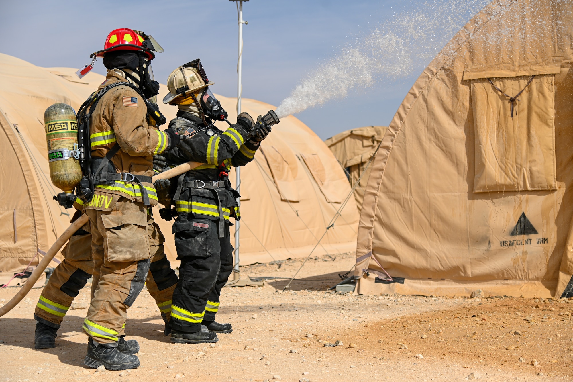 U.S. Air Force Staff Sgt. Sanjar Tursunov, left, 378th Expeditionary Civil Engineer Squadron firefighter, and Brig. Gen. Robert Davis, right, 378th Air Expeditionary Wing commander, extinguish a simulated structure fire at Prince Sultan Air Base, Kingdom of Saudi Arabia, Dec. 9, 2021. Airmen from the 378th ECES regularly participate in contingency readiness development to ensure that they are always prepared to answer the call. (U.S. Air Force photo by Staff Sgt. Christina Graves)