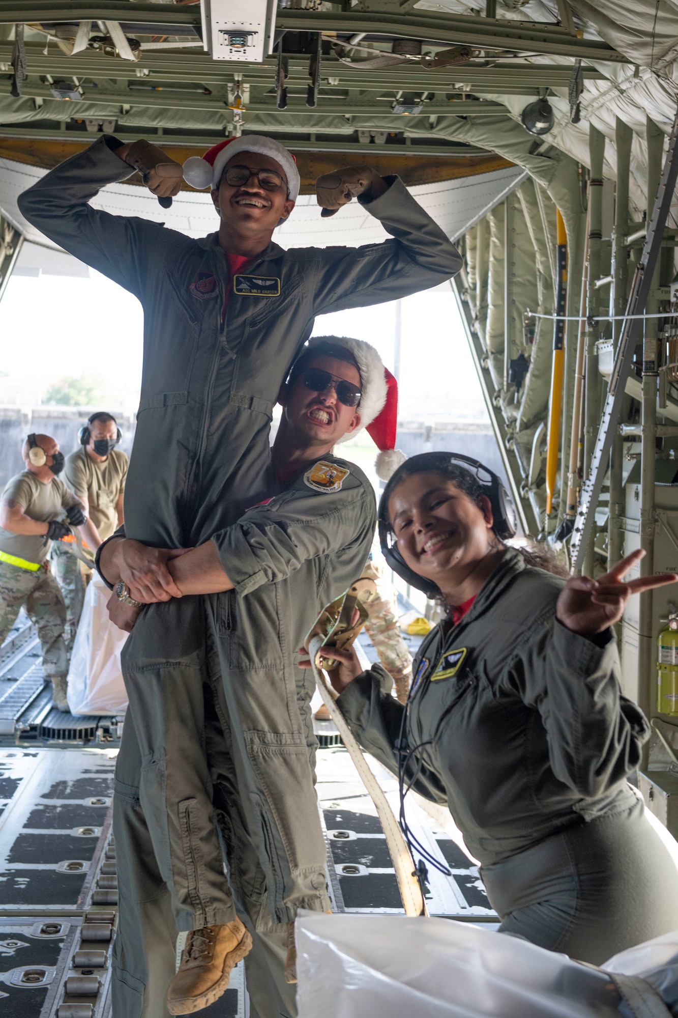 Airman 1st Class Milo Carter, left, Senior Airman Gabriela Arnspiger, right, 36th Airlift Squadron loadmasters and Capt. Stephen Sharp, 36th AS pilot, celebrate after successfully completing a day of bundles for the 70th Anniversary of Operation Christmas Drop drops at Andersen Air Force Base, Guam, Dec. 5, 2021. OCD is the Department of Defense’s longest-running humanitarian aid and disaster relief training mission and provides relief to more than 55 islands throughout the Pacific. Operations such as OCD provide the U.S. and its partners the opportunity to enhance joint operational capabilities and maintain preparedness for real-world emergencies. (U.S. Air Force photo by Tech. Sgt. Joshua Edwards)