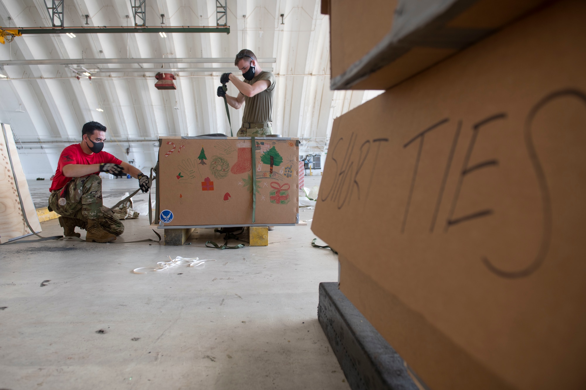 Senior Airman Kaine Kilburn, 374th Logistics Readiness Squadron combat mobility flight technician, right, and 1st Lt. Stephen Gardella, 374th LRS CMF commander, prepare a bundle during the 70th Anniversary of Operation Christmas Drop at Andersen Air Force Base, Guam, Dec. 8, 2021. OCD is the Department of Defense’s longest-running humanitarian aid and disaster relief training mission and provides relief to more than 55 islands throughout the Pacific. Operations such as OCD provide the U.S. and its partners the opportunity to enhance joint operational capabilities and maintain preparedness for real-world emergencies. (U.S. Air Force photo by Tech. Sgt. Joshua Edwards)