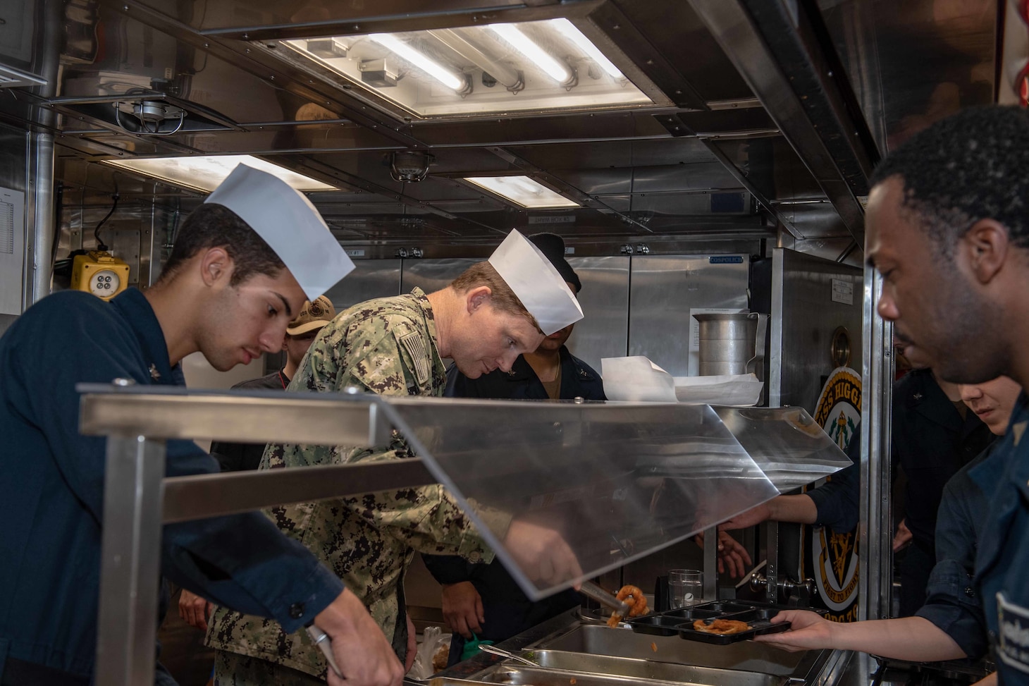 Lt. Matthew Moynihan, Chaplain aboard Arleigh Burke-class guided-missile destroyer USS Higgins (DDG 76) serves Sailors during a meal. Higgins is assigned to Commander, Task Force (CTF) 71/Destroyer Squadron (DESRON) 15, the Navy's largest forward-deployed DESRON and the U.S. 7th Fleet's principal surface force.