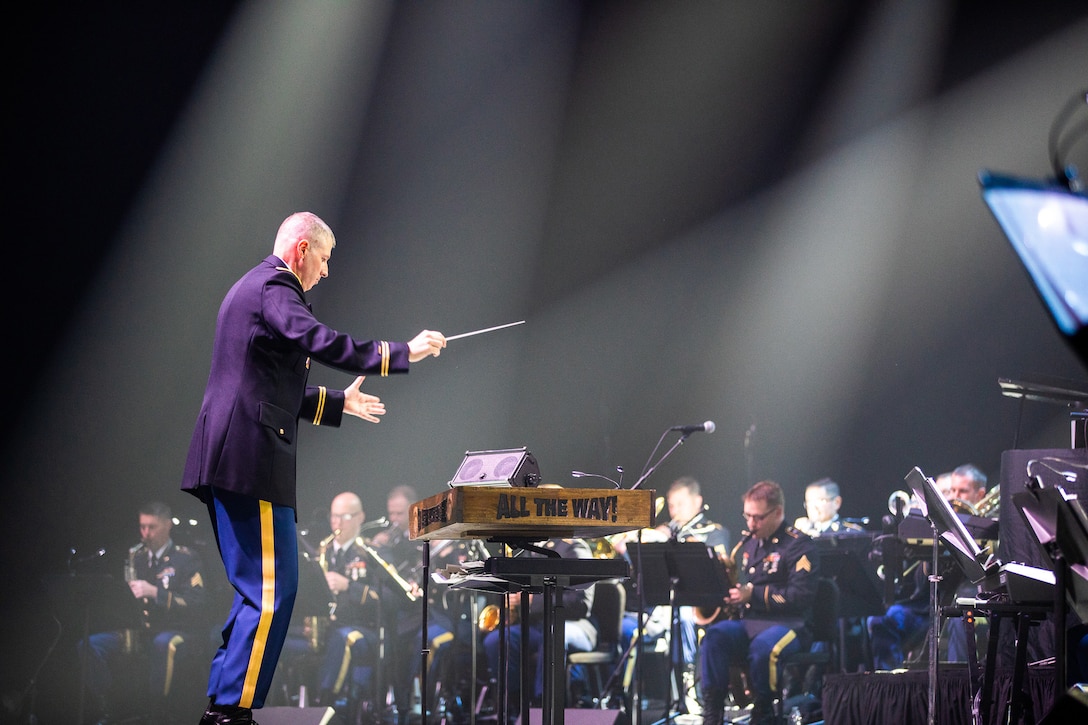 A man in a military uniform conducts a large band.