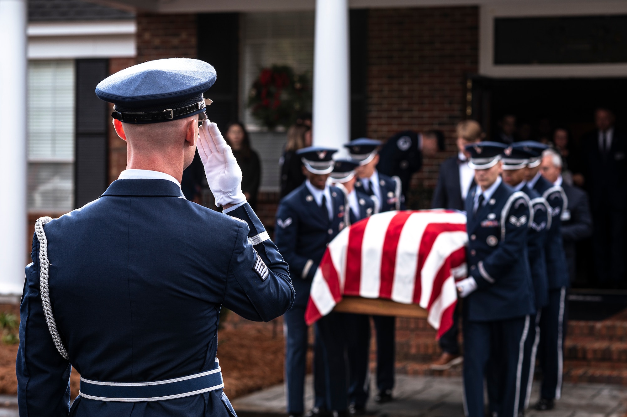 Photo of Airman saluting a casket being carried by other Airmen