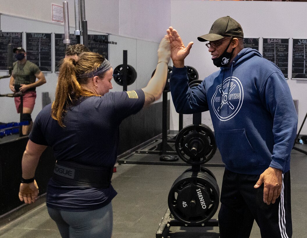 Sierra Dehart, Air Force Institute of Technology, exchanges a high-five with Rick Stanton, 88th Force Support Squadron recreation specialist, following her successful third squat in a powerlifting competition in the Wright Field Fitness Center Dec. 11, 2020, at Wright-Patterson Air Force Base. Dehart went on to win the women’s portion of the event. (U.S. Air Force photo by R.J. Oriez)