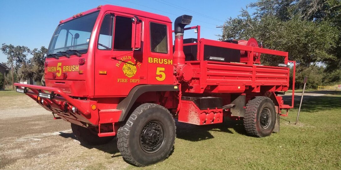 A onetime military truck now converted into a firetruck painted red.