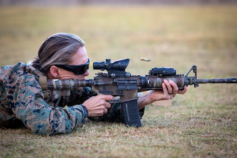 A Marine fires a weapon while laying on the ground.
