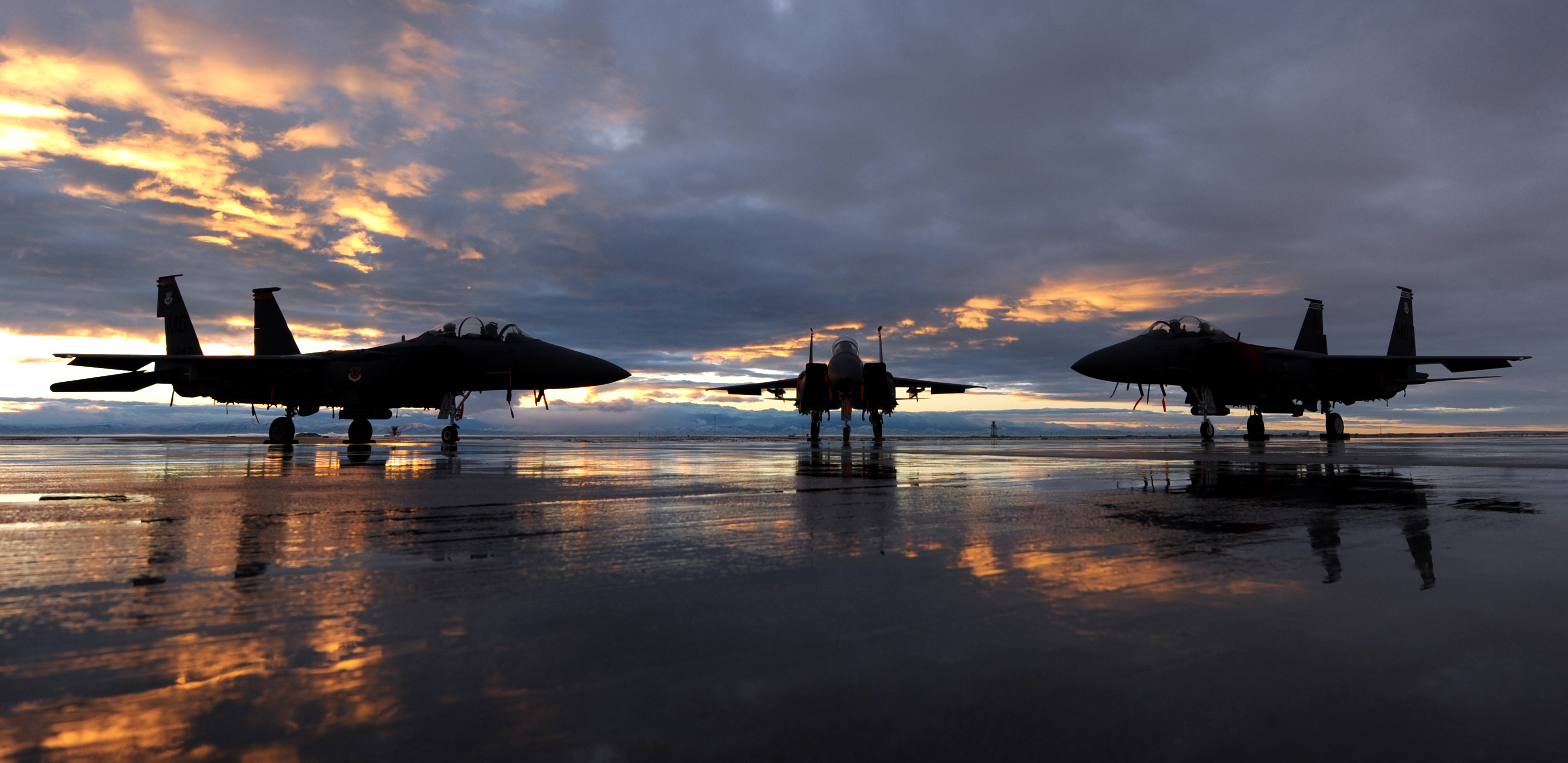 Two F-15E Strike Eagles assigned to the 391st and 389th Fighter Squadrons and one F-15SG assigned to the 428th Fighter Squadron sit on the flightline during sunset