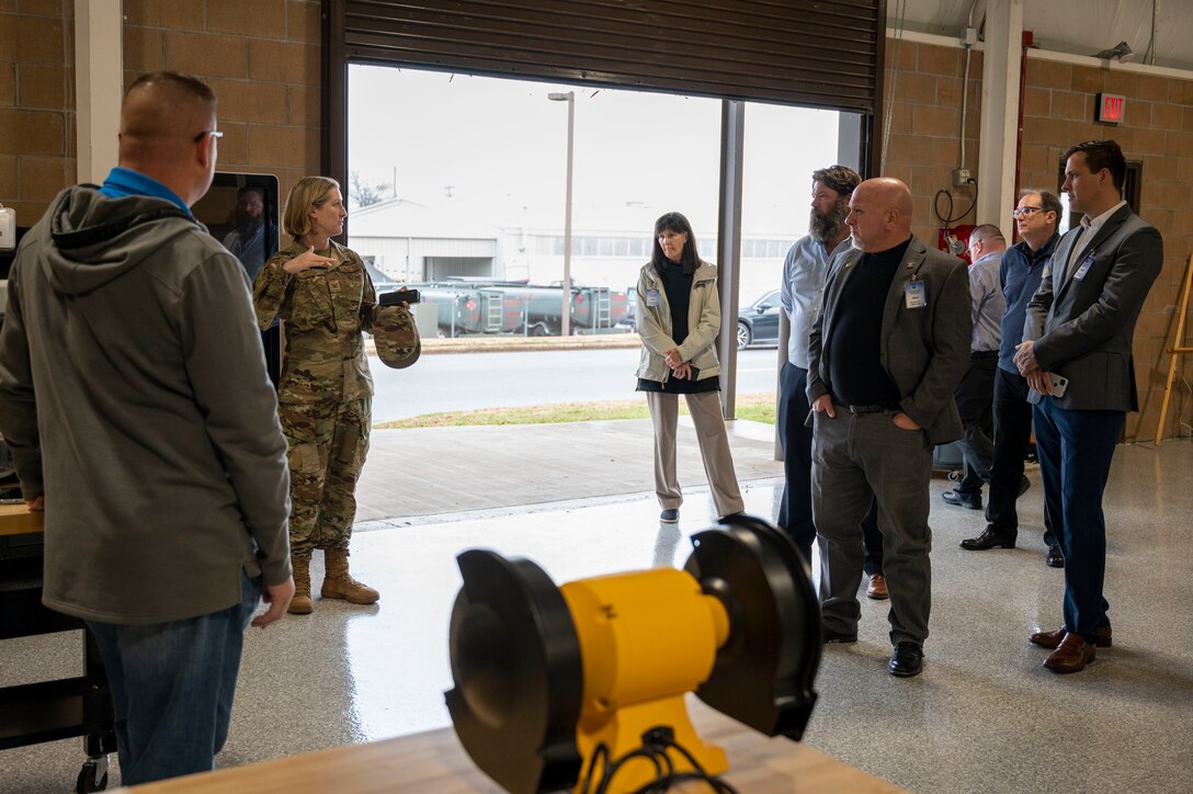 The installation commander speaks with honorary commanders in a hangar.
