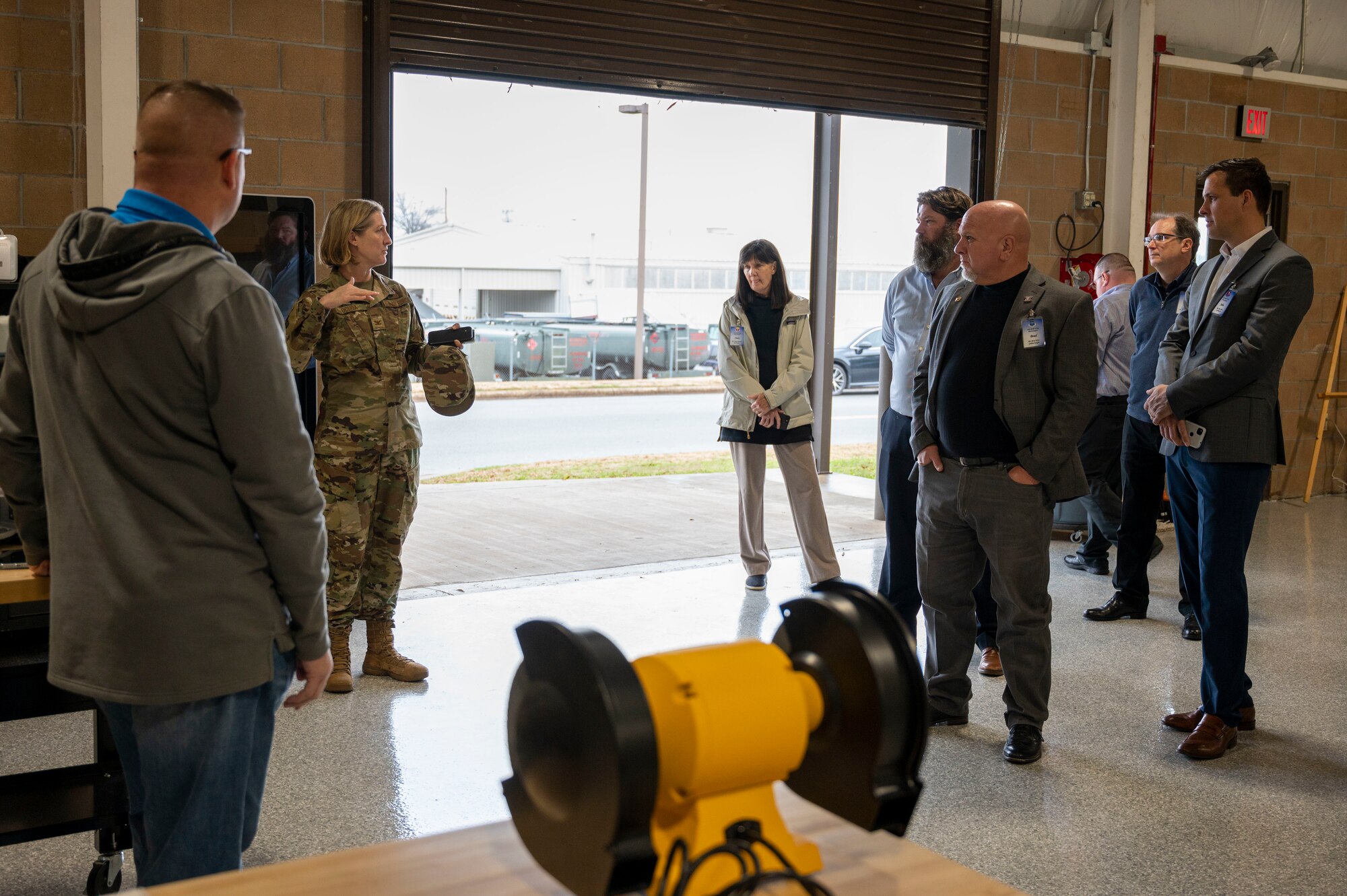 The installation commander speaks with honorary commanders in a hangar.