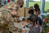 Col. Paige M. Jennings, U.S. Army Financial Management Command commander, and Command Sgt. Maj. Kenneth F. Law, USAFMCOM senior enlisted advisor, hand out gifts at a local childcare center in Indianapolis Dec. 13, 2021. Together, the USAFMCOM leadership team handed out special holiday presents to approximately 85 students. (U.S. Army photo by Mark R. W. Orders-Woempner)