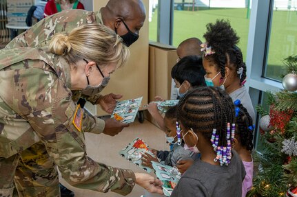 Col. Paige M. Jennings, U.S. Army Financial Management Command commander, and Command Sgt. Maj. Kenneth F. Law, USAFMCOM senior enlisted advisor, hand out gifts at a local childcare center in Indianapolis Dec. 13, 2021. Together, the USAFMCOM leadership team handed out special holiday presents to approximately 85 students. (U.S. Army photo by Mark R. W. Orders-Woempner)
