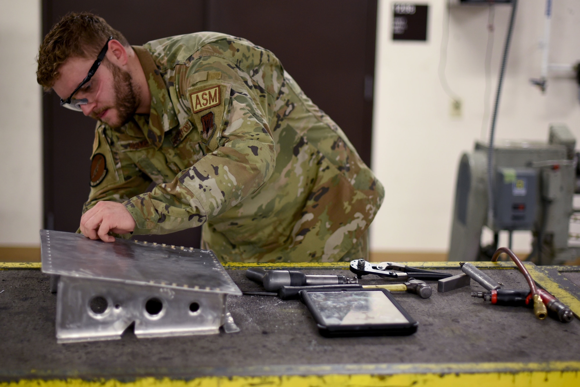 Senior Airman Jacob Adams, 24th Fighter Squadron Aircraft Structural Maintenance craftsman, prepares his workspace prior to riveting training in the ASM shop at U.S. Naval Air Station Joint Reserve Base Fort Worth, Texas on Dec. 14, 2021. The mission of the 301st Fighter Wing is to train and deploy combat ready Airmen. (U.S. Air Force photo by Staff Sgt. Randall Moose)