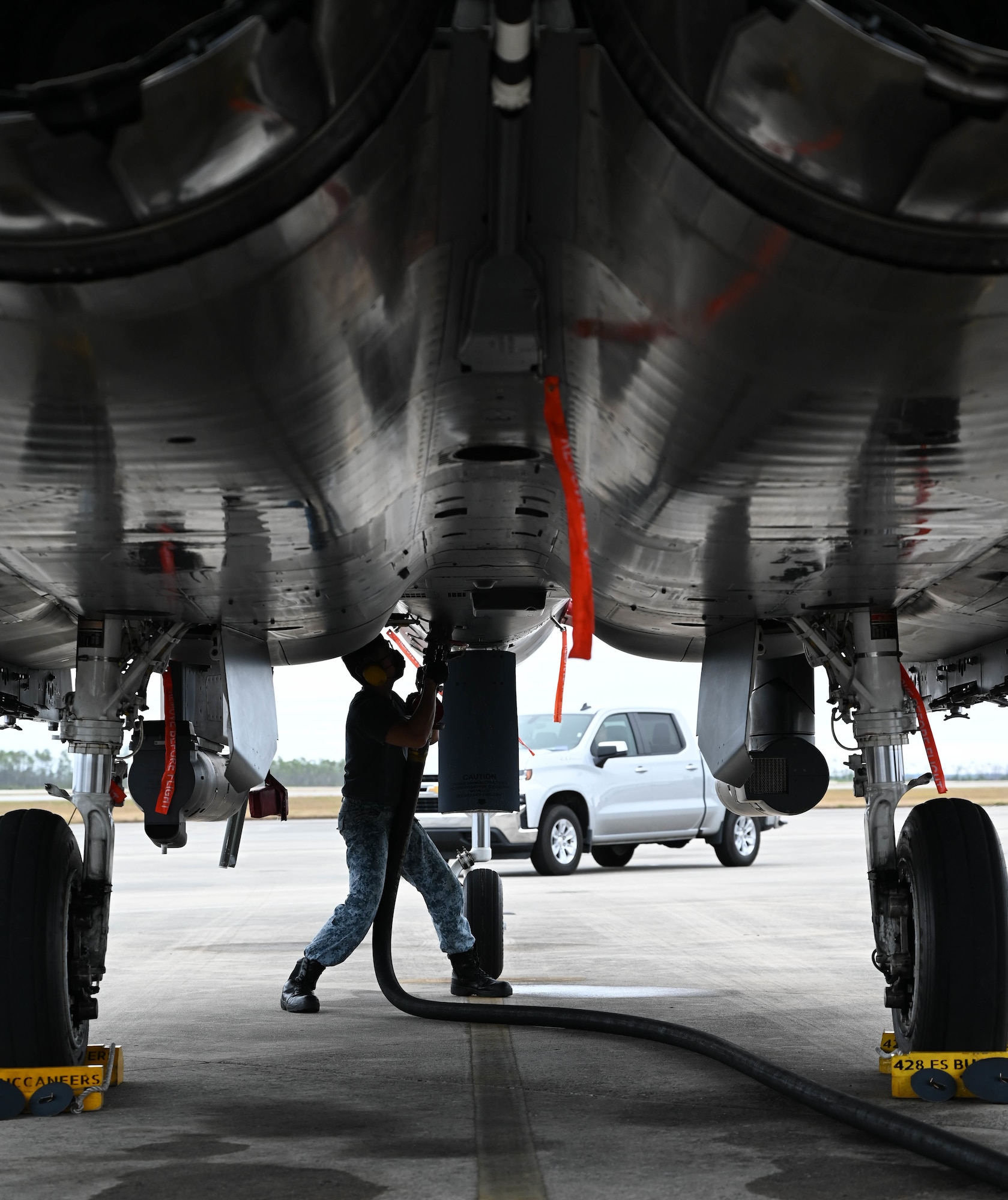An airman connects a fuel hose to an aircraft