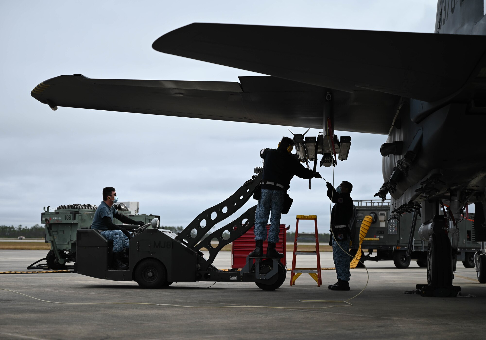 An airman connects a hose to an aircraft