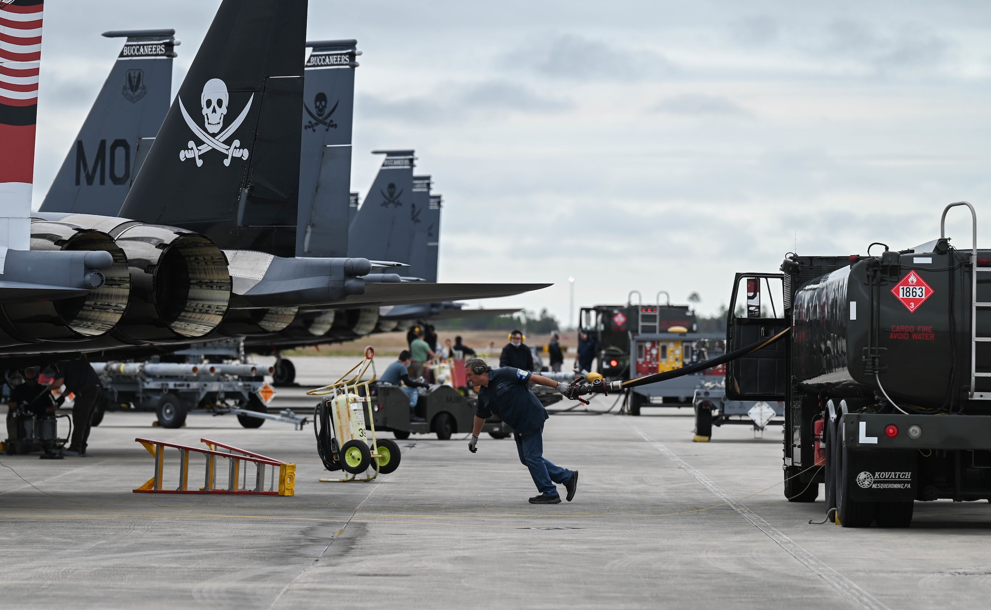 A member of the 428th Fighter Squadron pulls a hose towards an aircraft