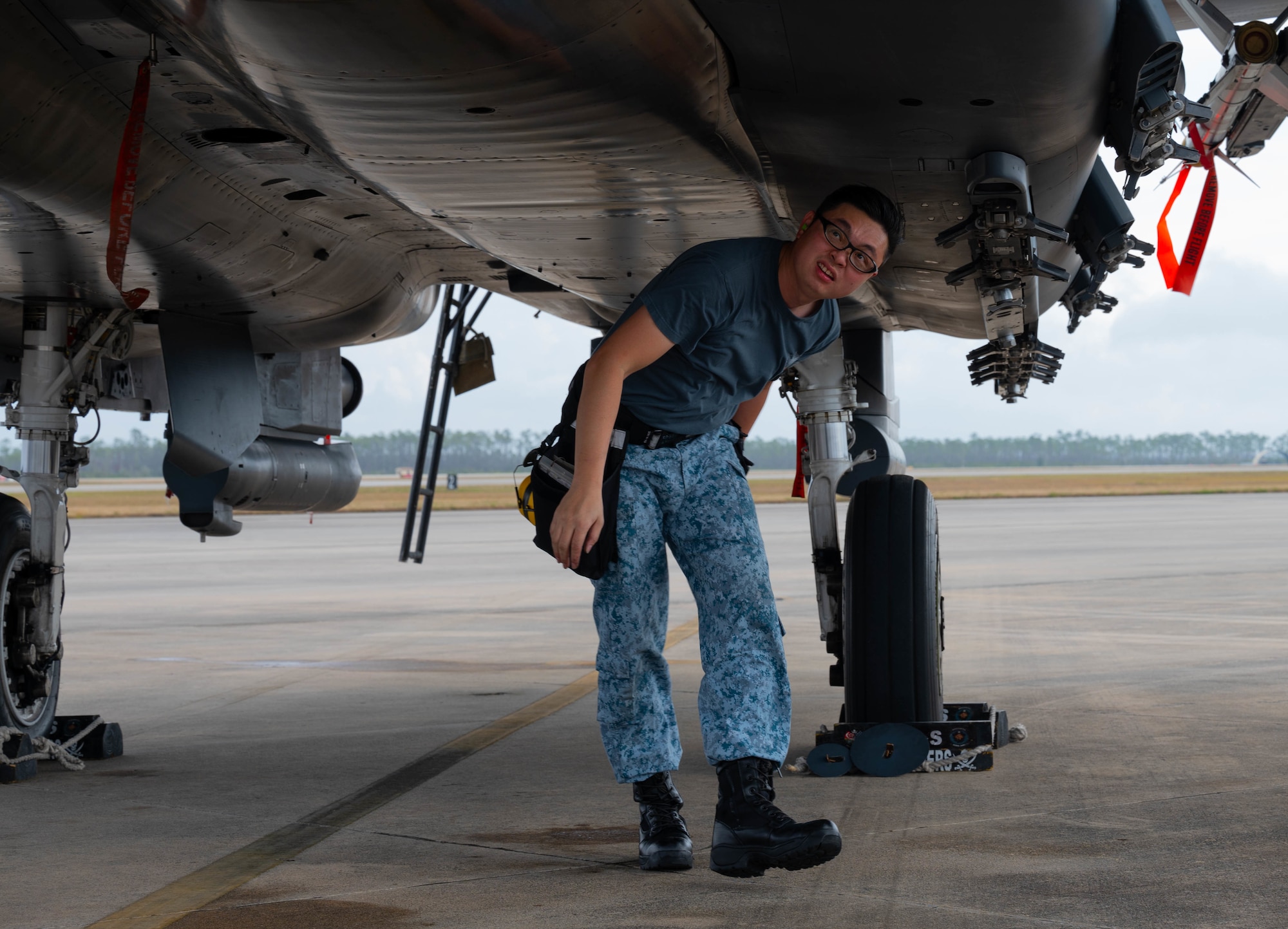 An airman performs an inspection on an aircraft