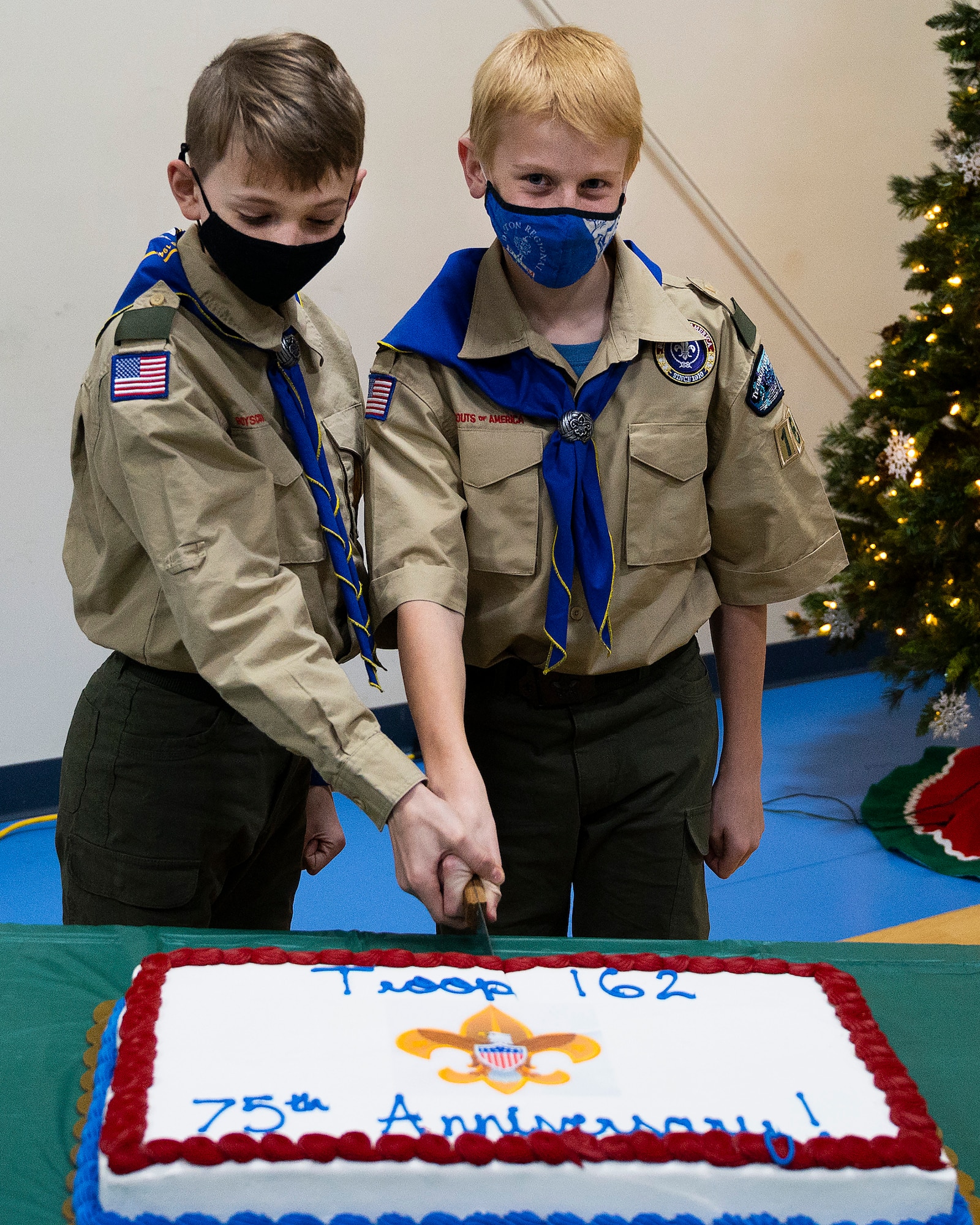 Alexander D’Agostino (left), 11, and Isaiah Hunter, 11, cut a cake commemorating the 75th anniversary of Boy Scout Troop 162 in Fairborn, Ohio, Dec. 13, 2021. Both boys and most others in the troop have a parent attached to, or working at, Wright-Patterson Air Force Base. (U.S. Air Force photo by R.J. Oriez)