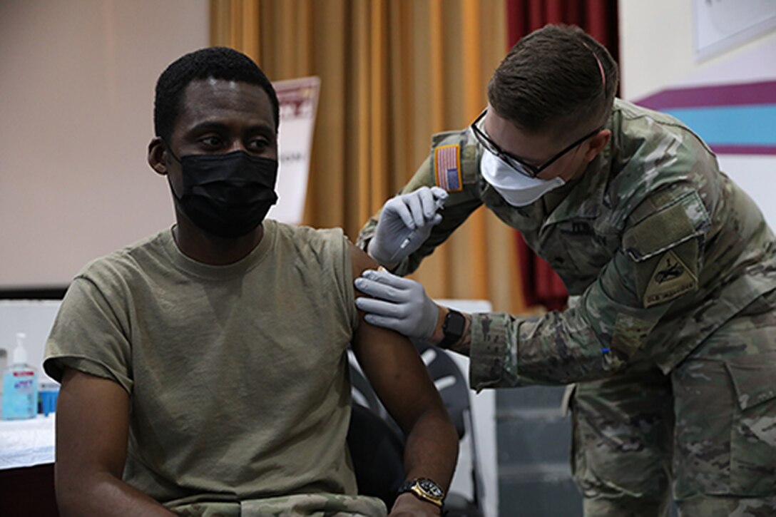 A soldier is vaccinated by another soldier.